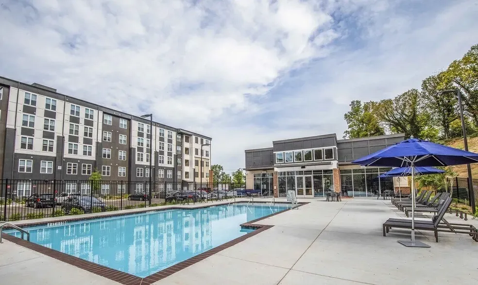 Apartment building with a swimming pool and lounge chairs.
