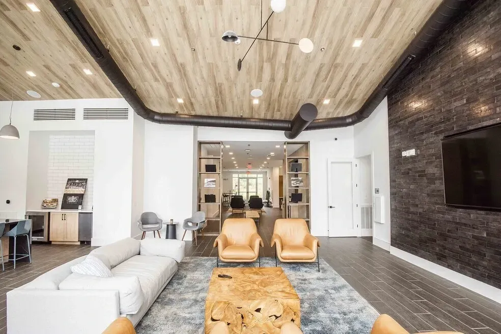 Modern lobby lounge area with comfortable seating, coffee bar, and large TV.