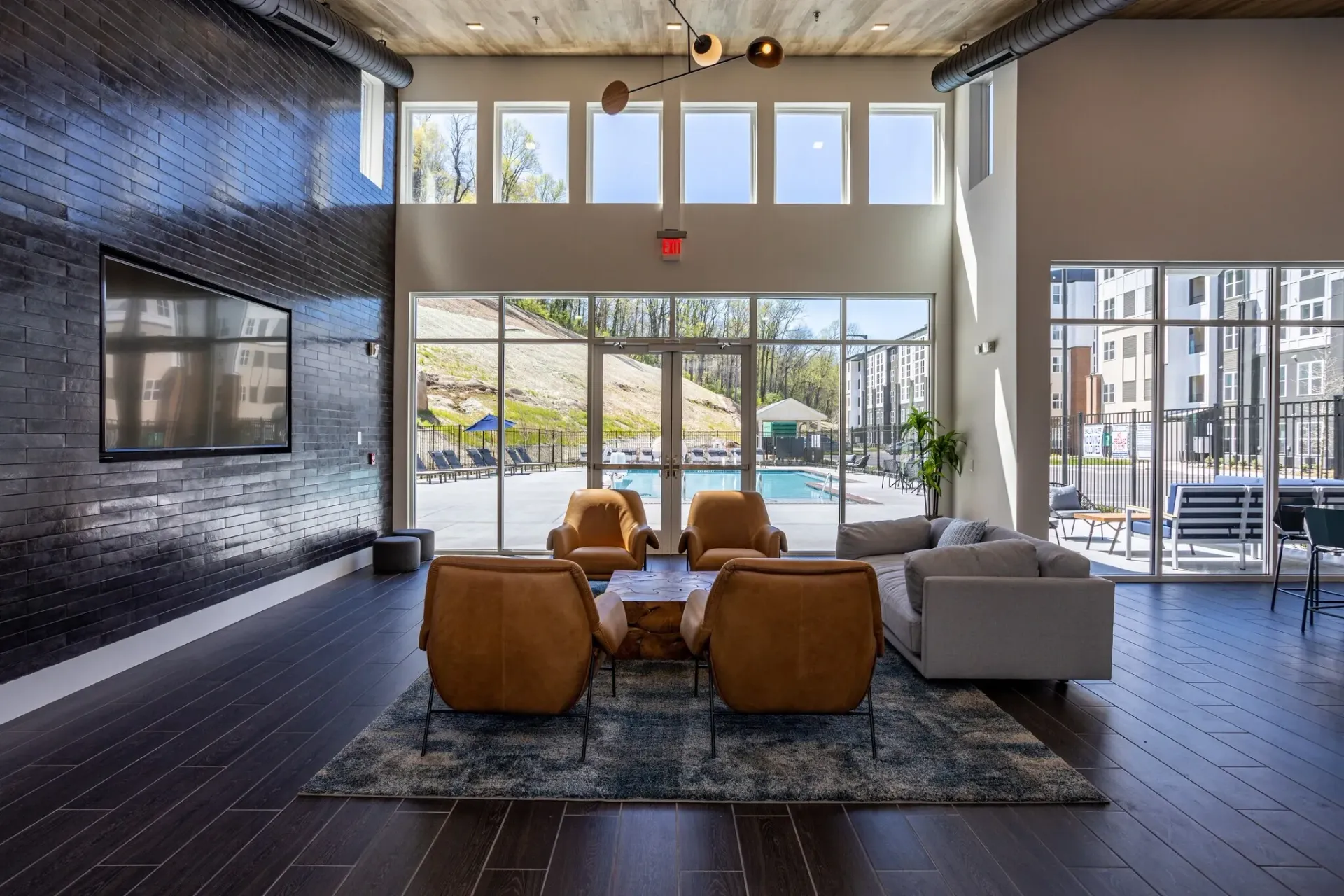 Community lounge area with seating and view of pool and apartment buildings.
