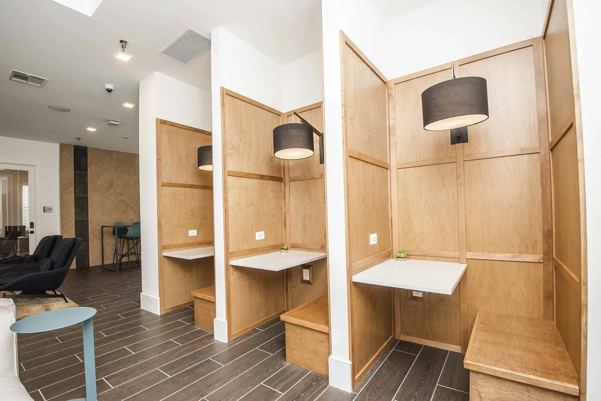 Private work booths with desks and seating in a common area.