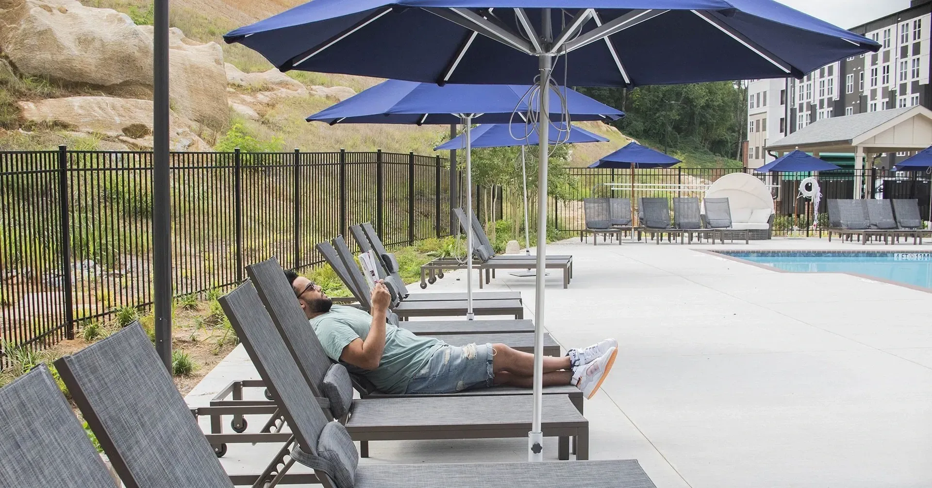 Man relaxing by the pool on a lounge chair.