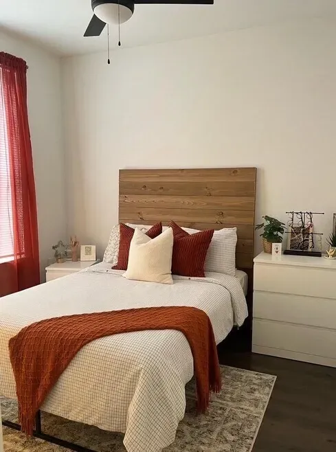 Bedroom with a queen-size bed, white dresser, and red curtains.