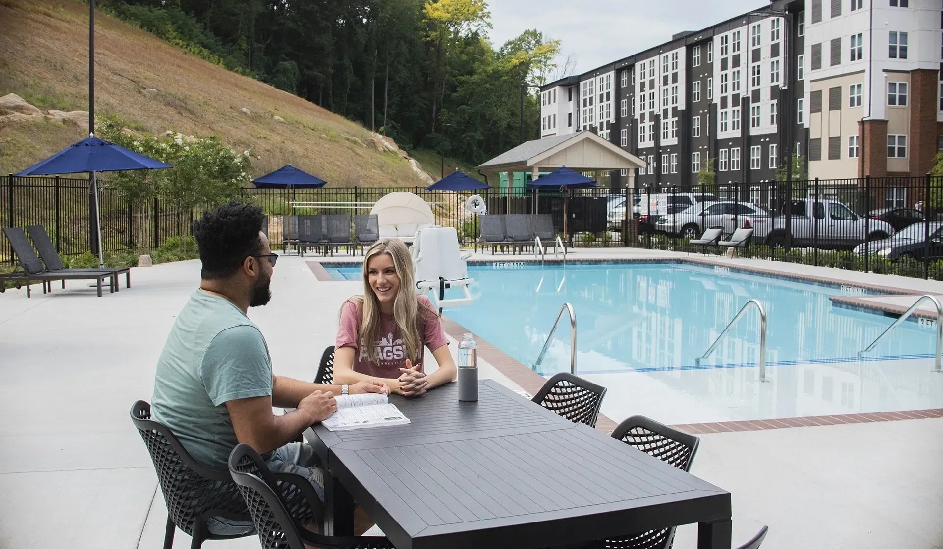 People sitting at a table by the pool at a multifamily property.