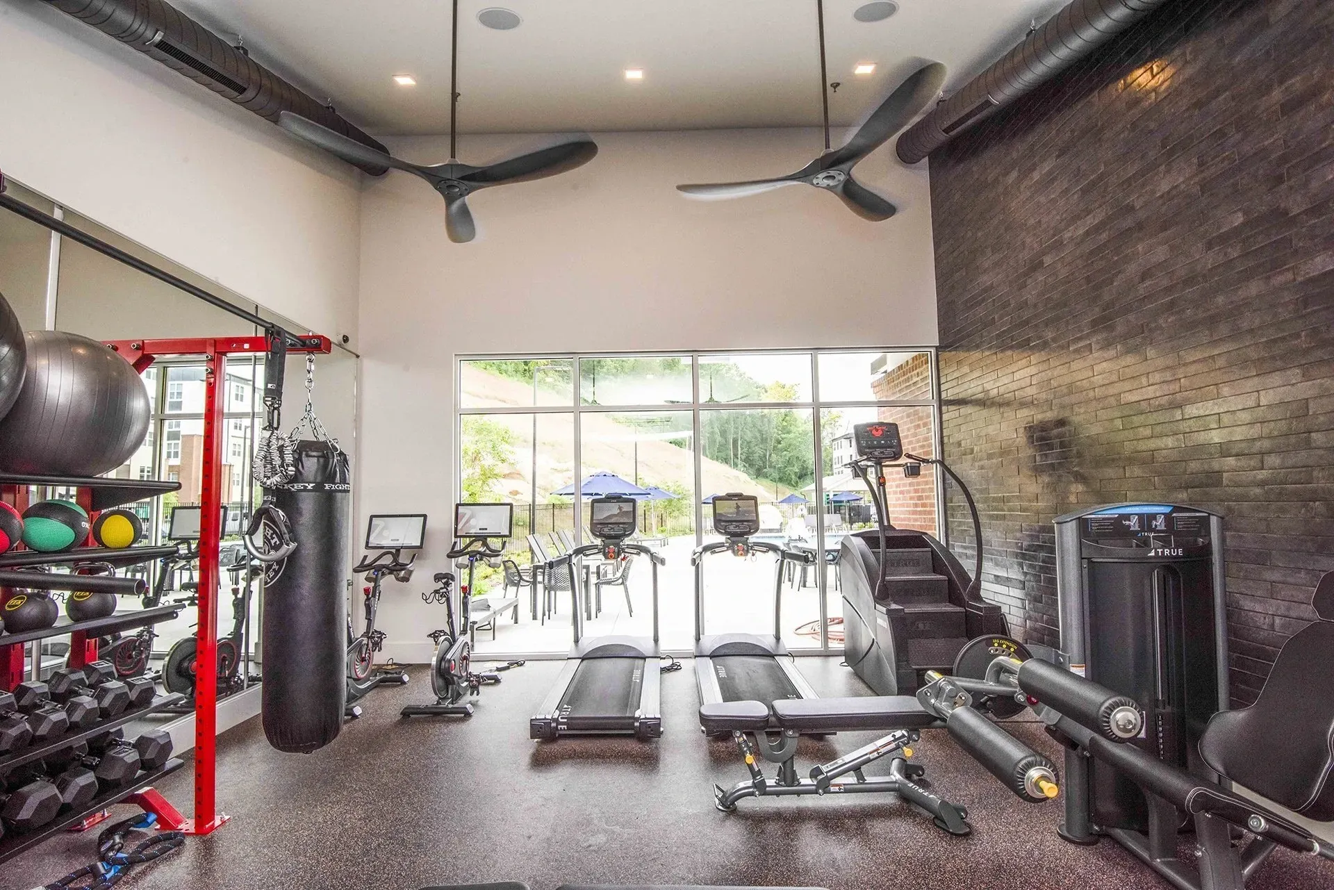 Modern fitness center with treadmills, bikes, weights, and punching bag.