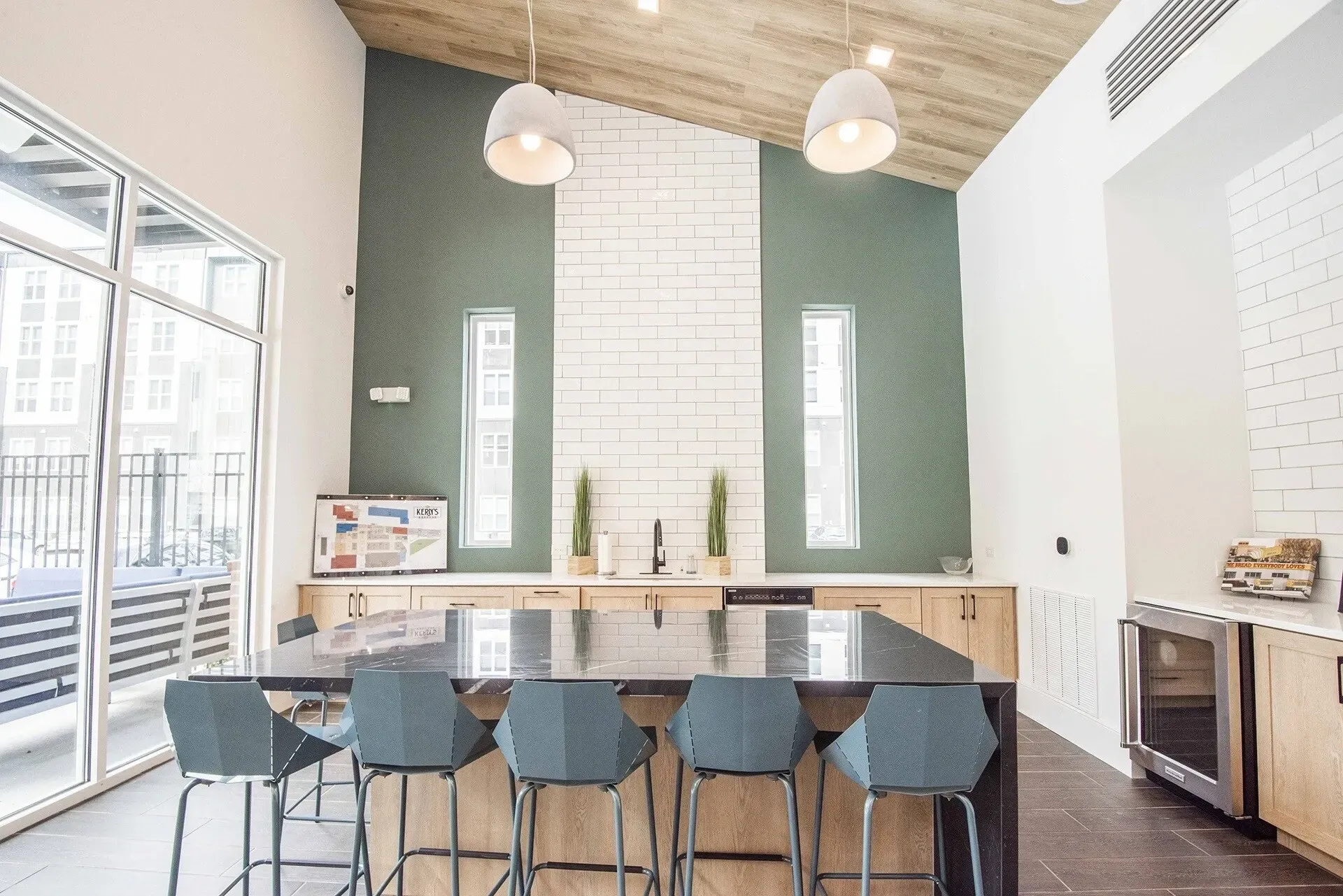 Modern communal kitchen area with island, bar stools, and wine fridge.