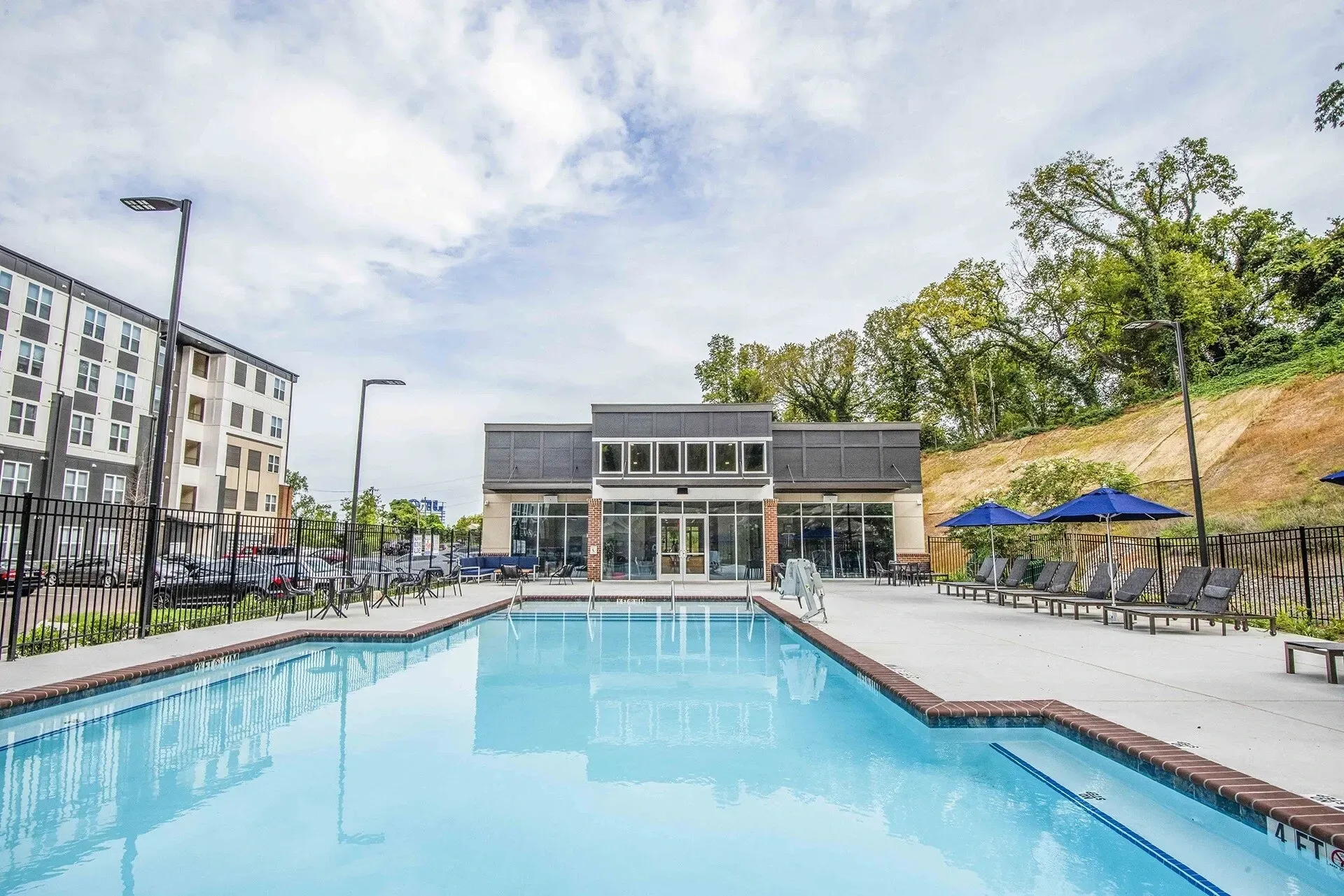 Apartment community swimming pool with lounge chairs and umbrellas