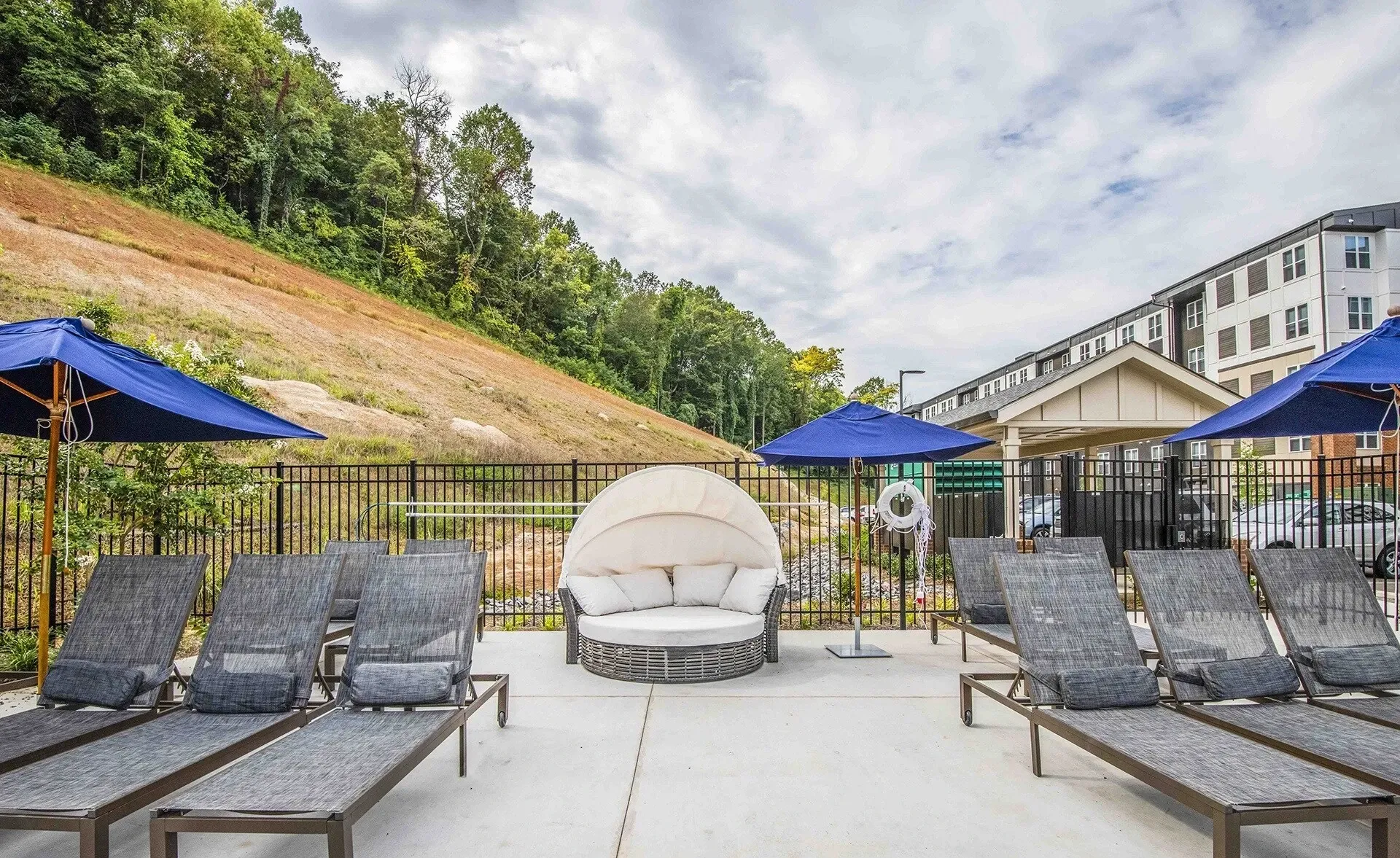 Outdoor lounge area with chaise lounges and canopy daybed near a building.
