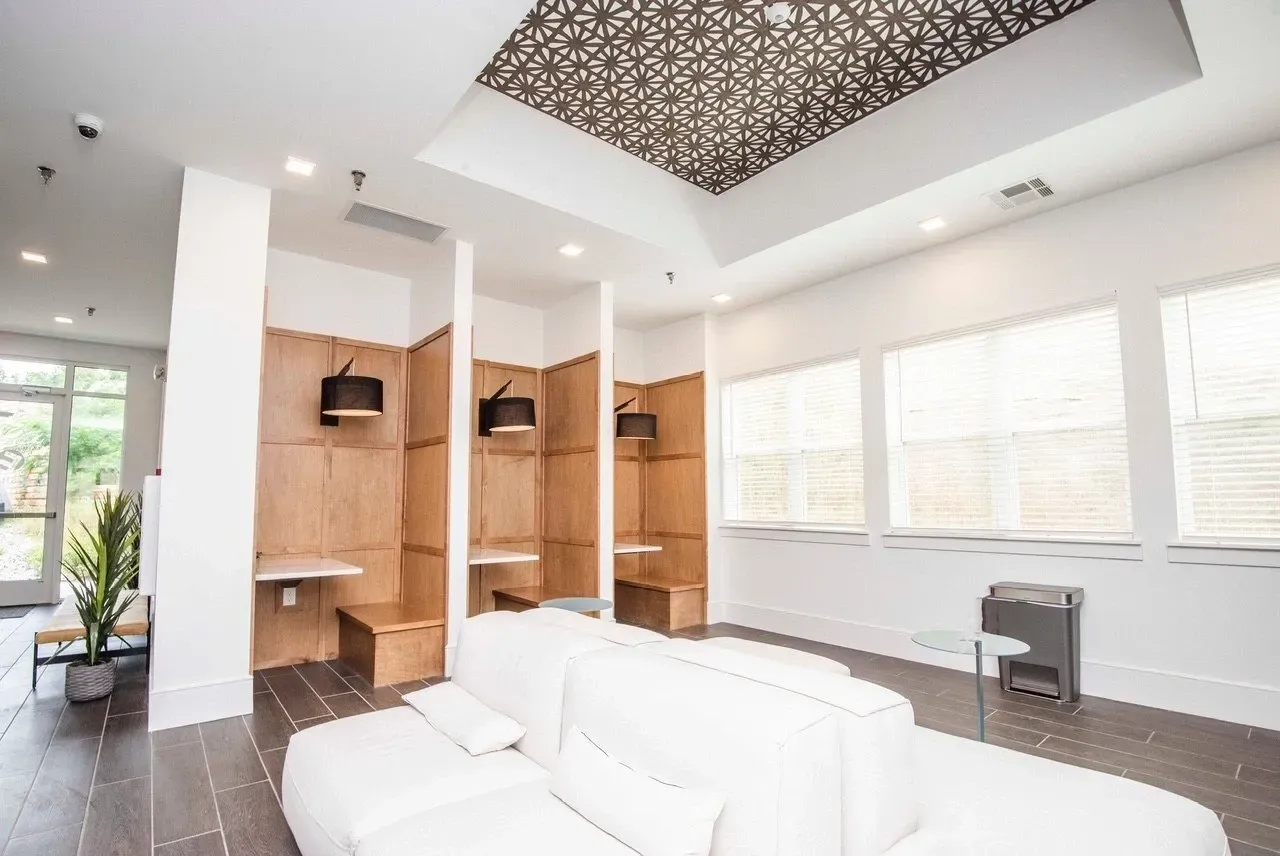 Modern lounge area with white modular sofas, wood-paneled work nooks, and decorative ceiling.