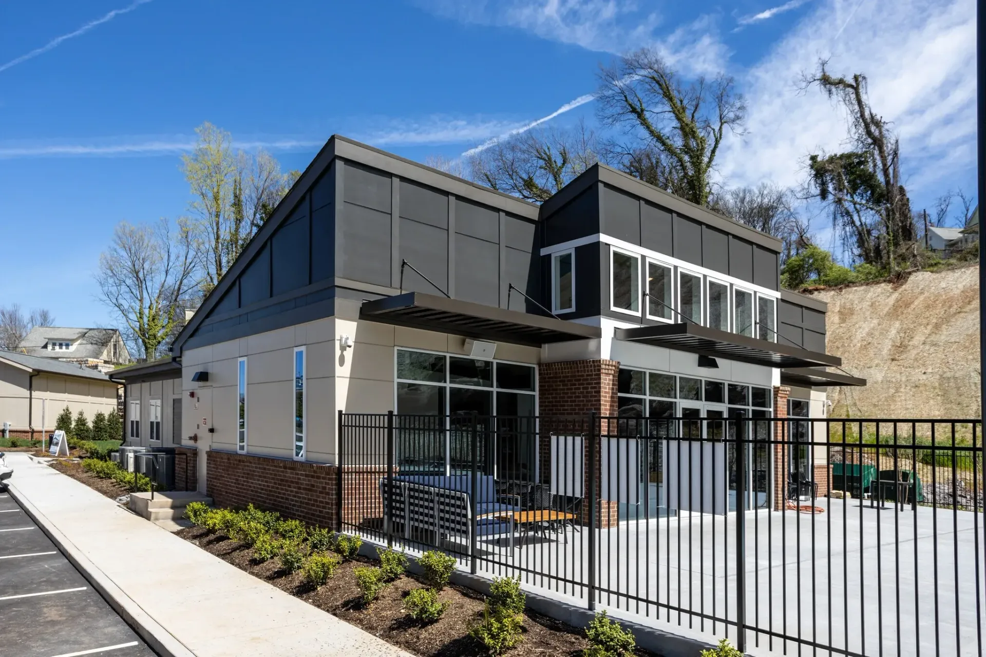 Modern building exterior with large windows and a fenced outdoor seating area.