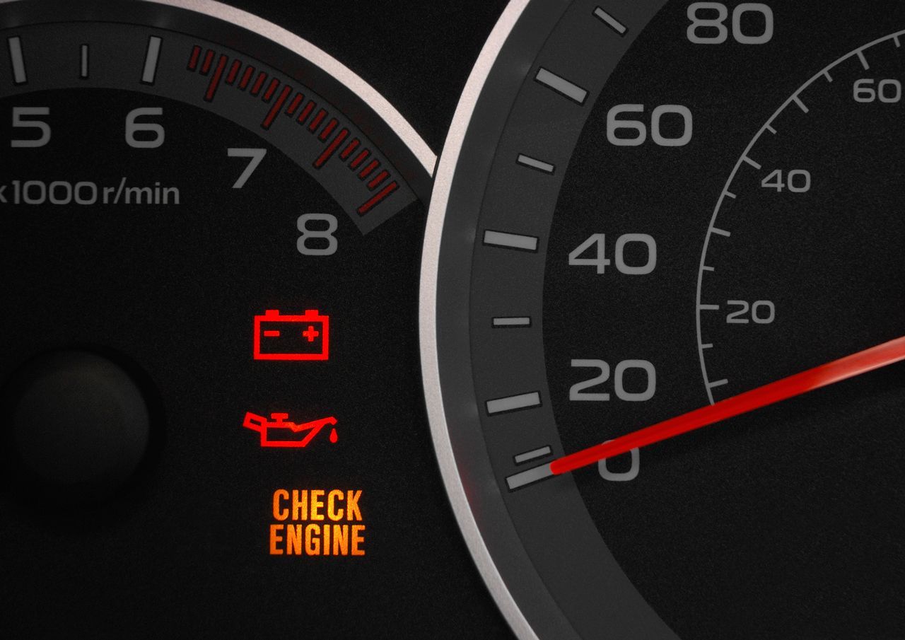 A check engine light is lit up on the dashboard of a car