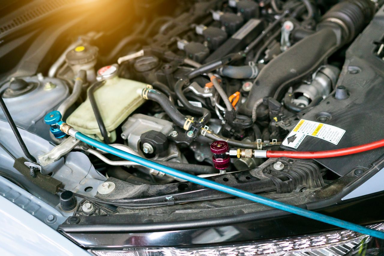 A close up of a car engine with a hose attached to it.