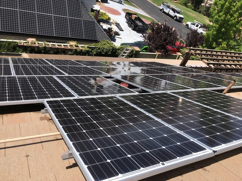 Solar panels installed on a rooftop with a garden and trees in the background