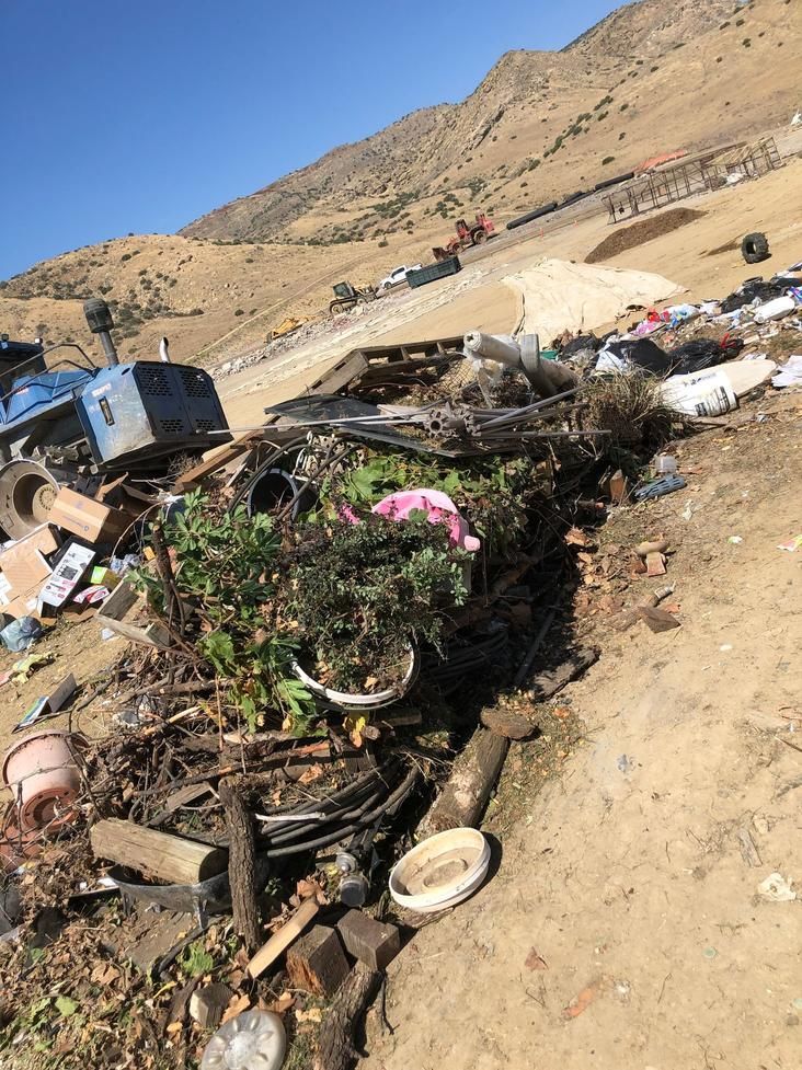 Burning trash pile beside a dirt road in a dry, hilly landscape