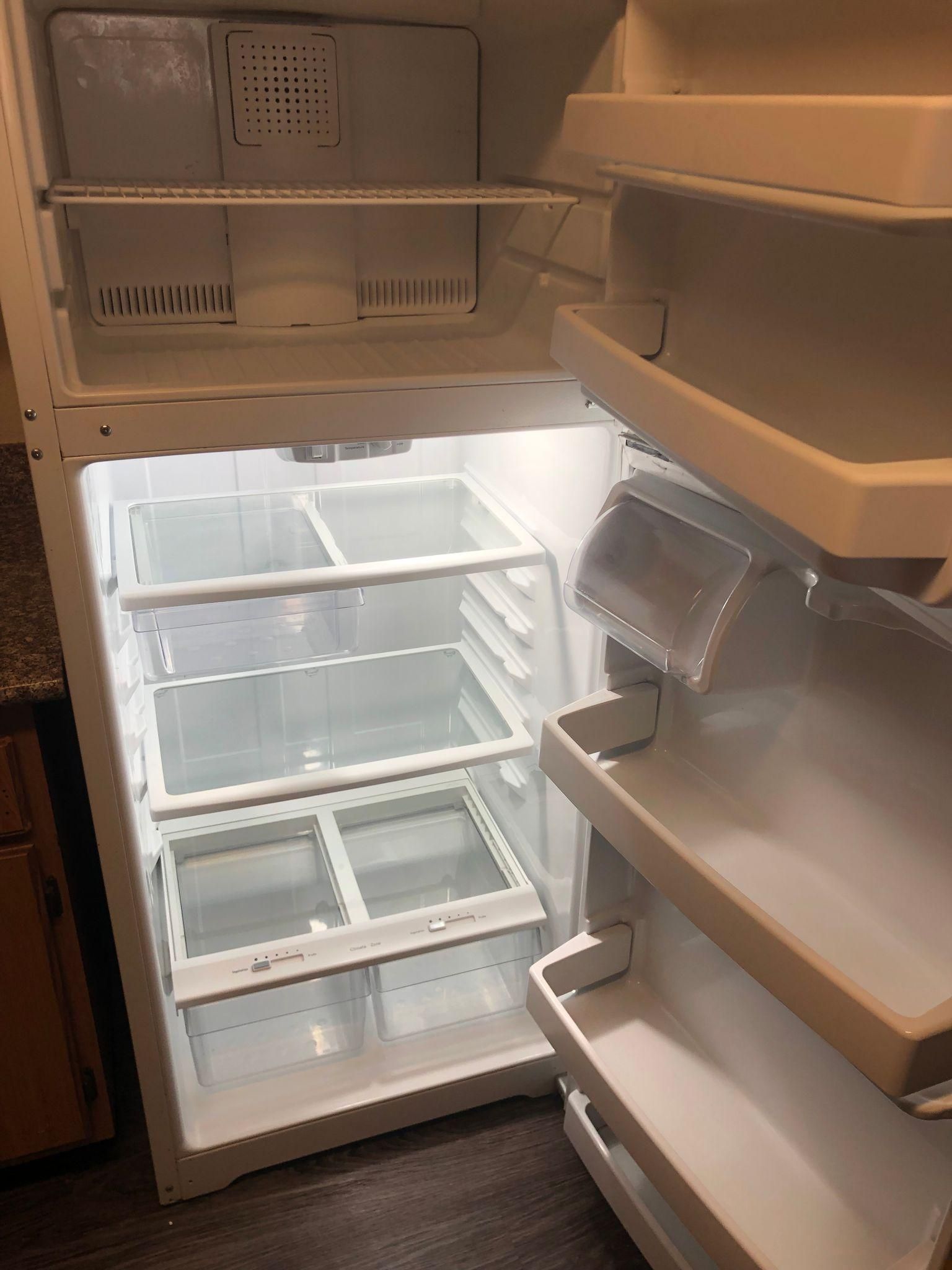 Open refrigerator with empty glass shelves and door bins lit from inside