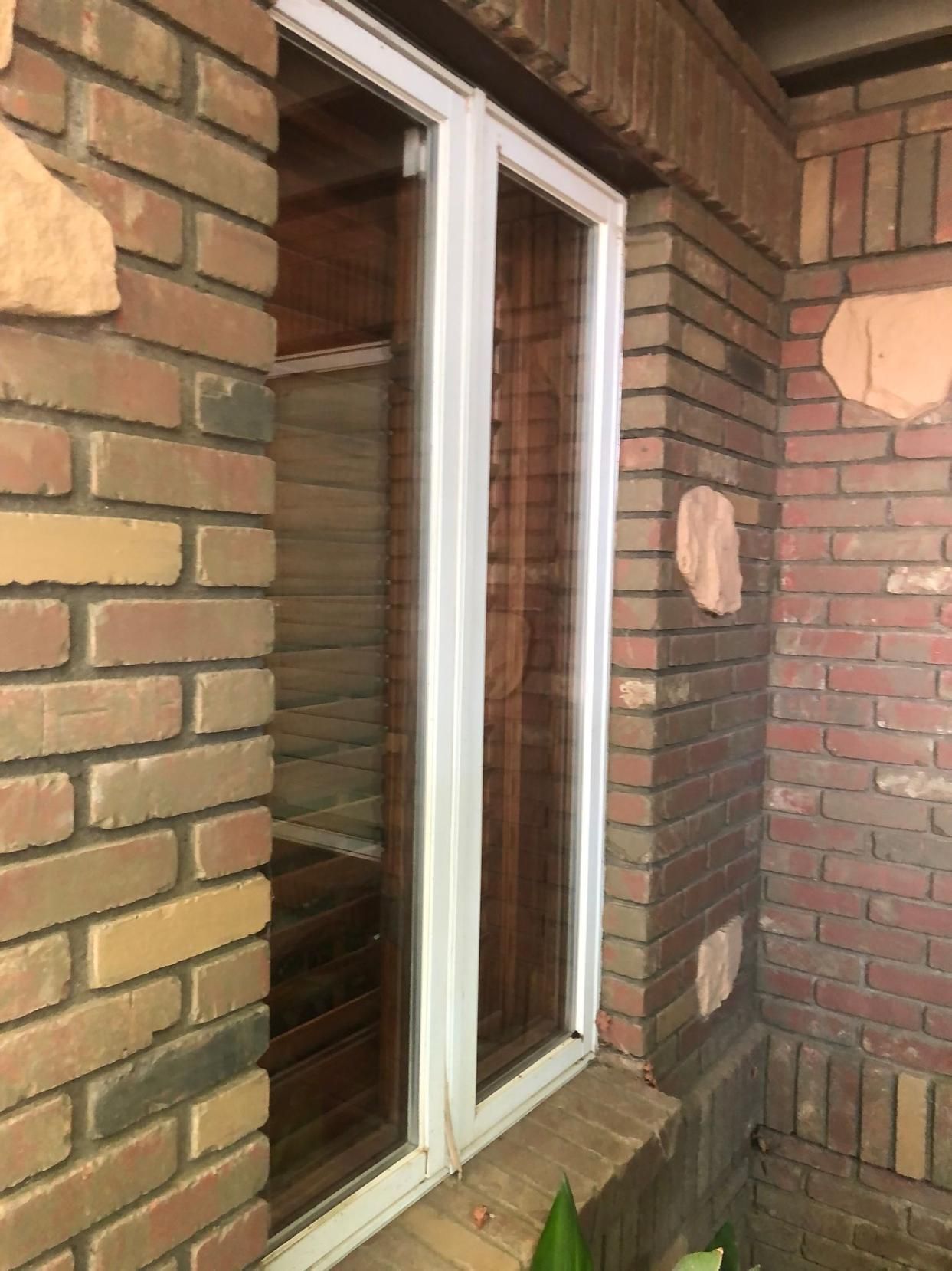 Brick house exterior with a white-framed window and brick wall details