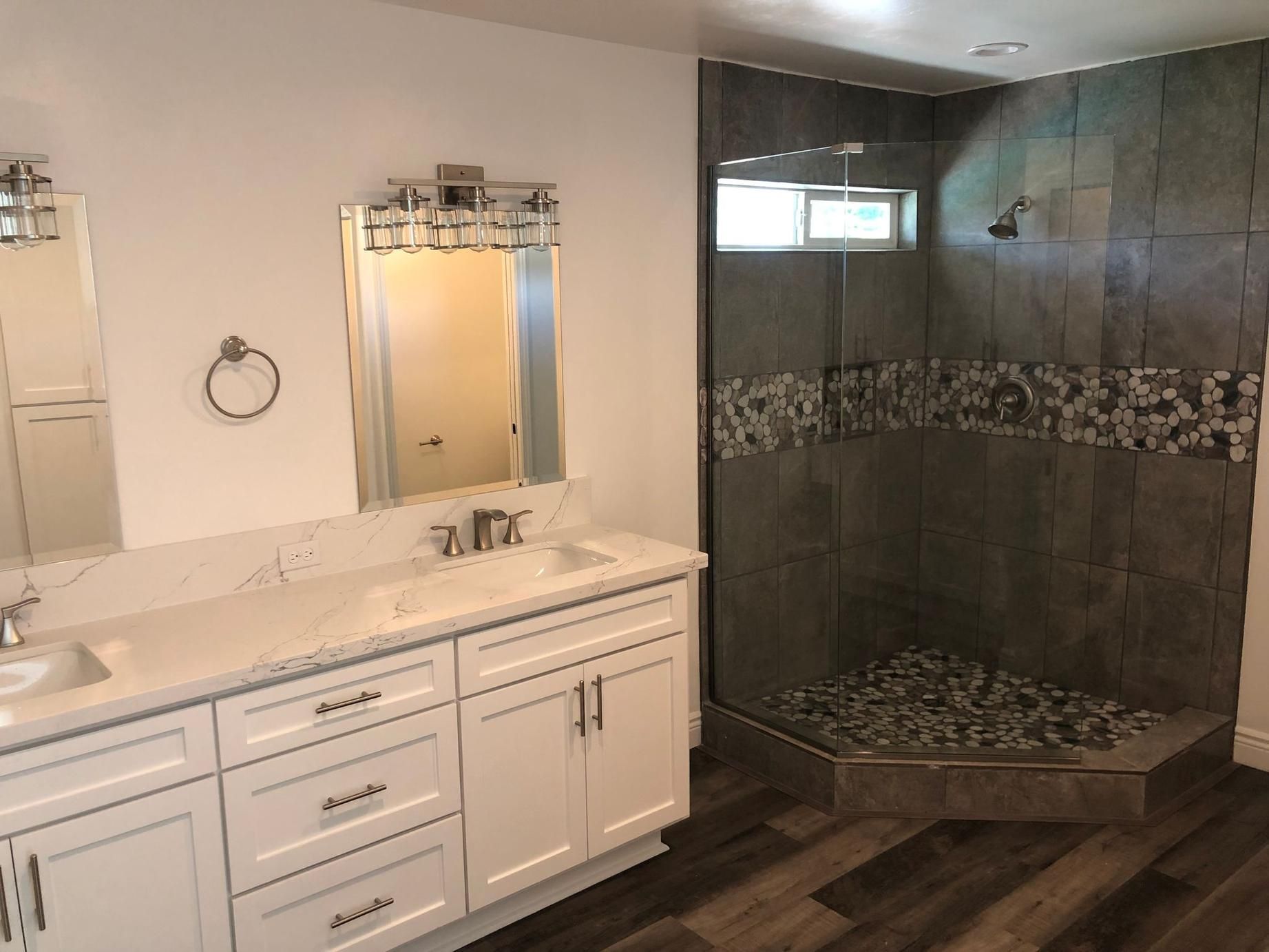 Bathroom with white vanity and mirror on the left, and a tiled glass shower on the right.