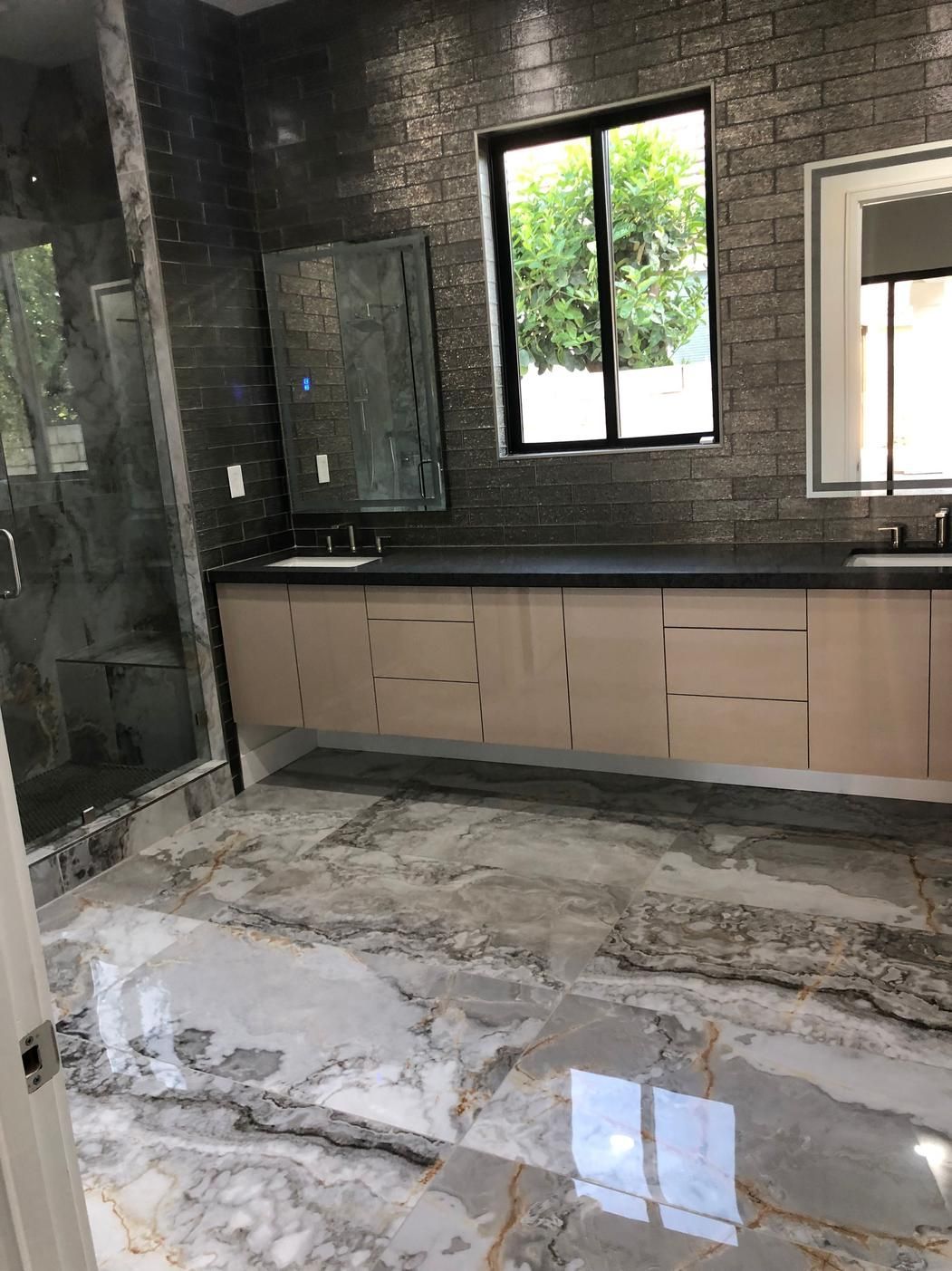 Bathroom under renovation with dark tiled walls, unfinished vanity, and wet concrete floor