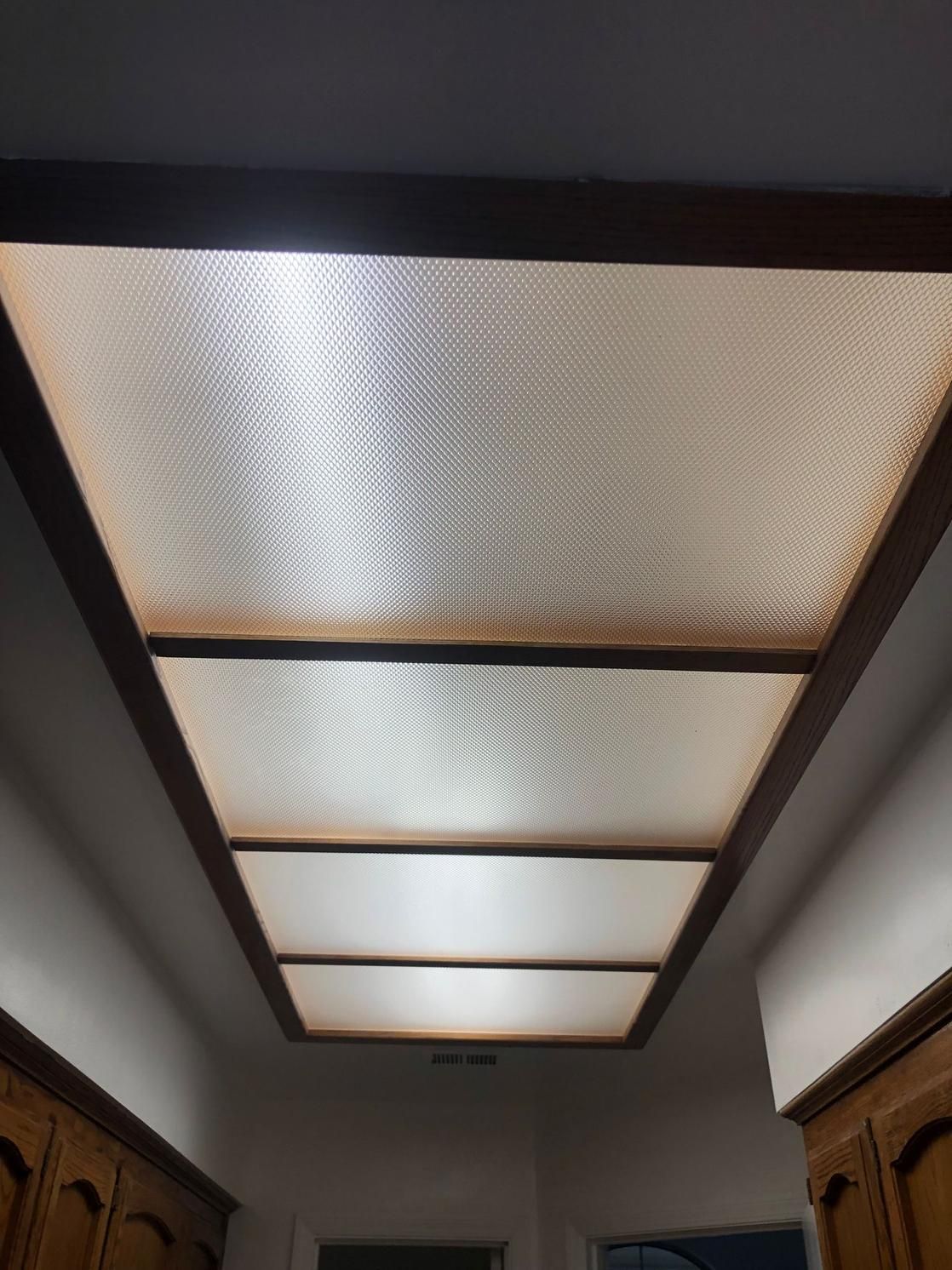 Ceiling light panels in a hallway with frosted, patterned glass and dark trim