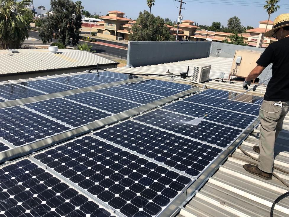 Solar panels on a rooftop with a person inspecting them under a clear sky