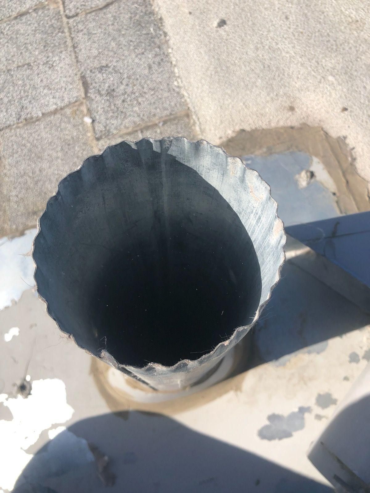 Open metal-lined hole in a pavement or sidewalk, viewed from above.