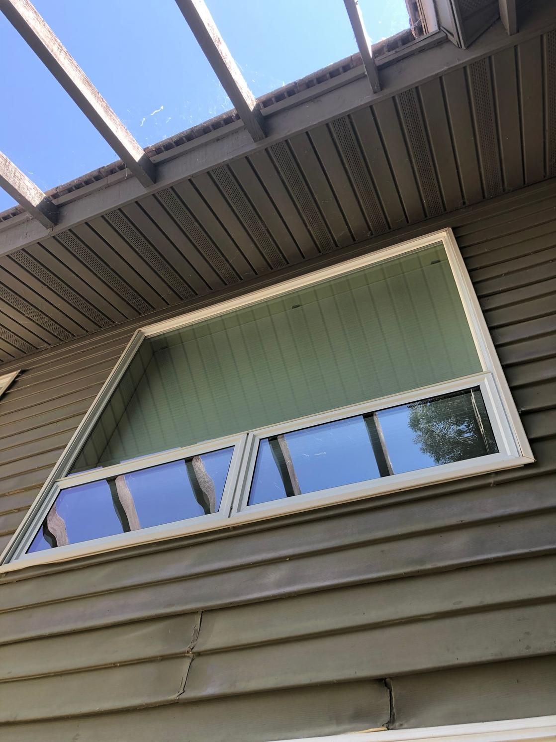 Exterior view of house siding and windows under the roof overhang