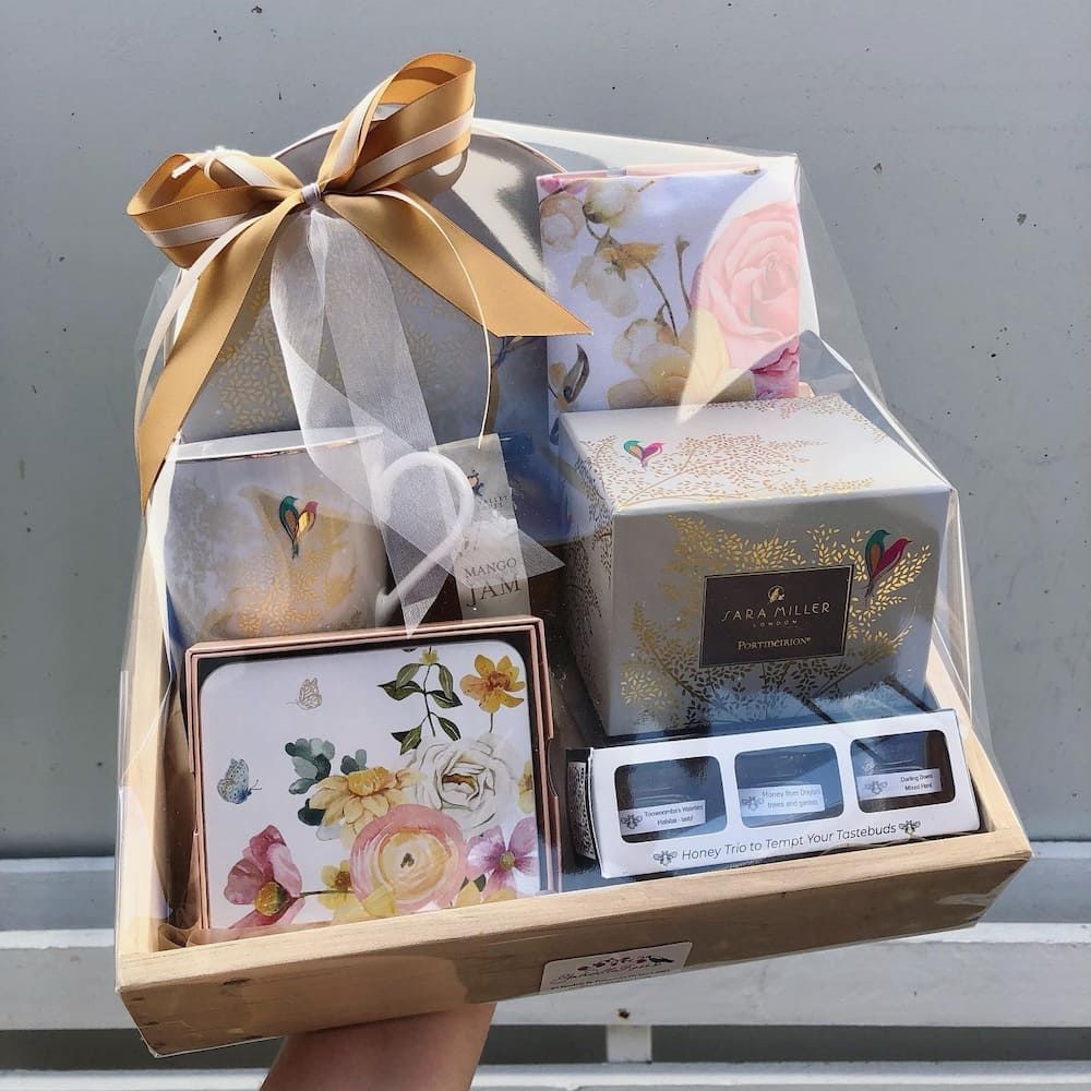 A Person Is Holding A Gift Basket With Flowers On It — Clover Country Flowers and Gifts In Toowoomba, QLD