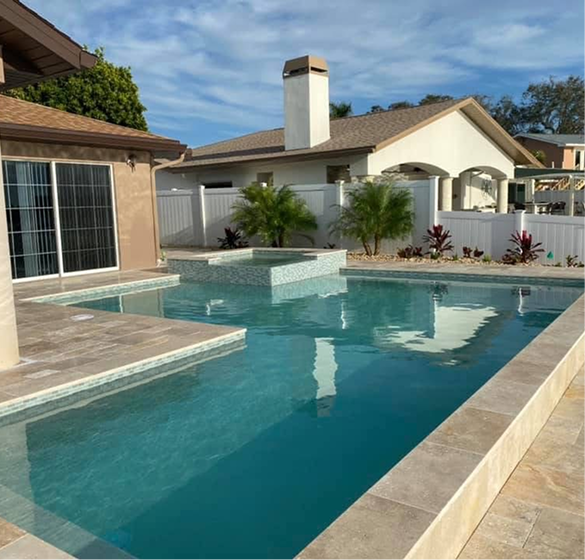 A rectangular pool with turquoise water, a connected spa, and a house in the background. Sunny day.