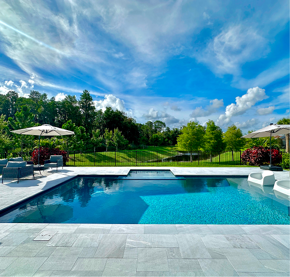 A rectangular pool with turquoise water, a connected spa, and a house in the background. Sunny day.