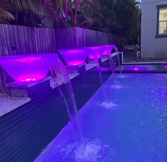 Pool steps with blue and iridescent mosaic tiles submerged in clear water.