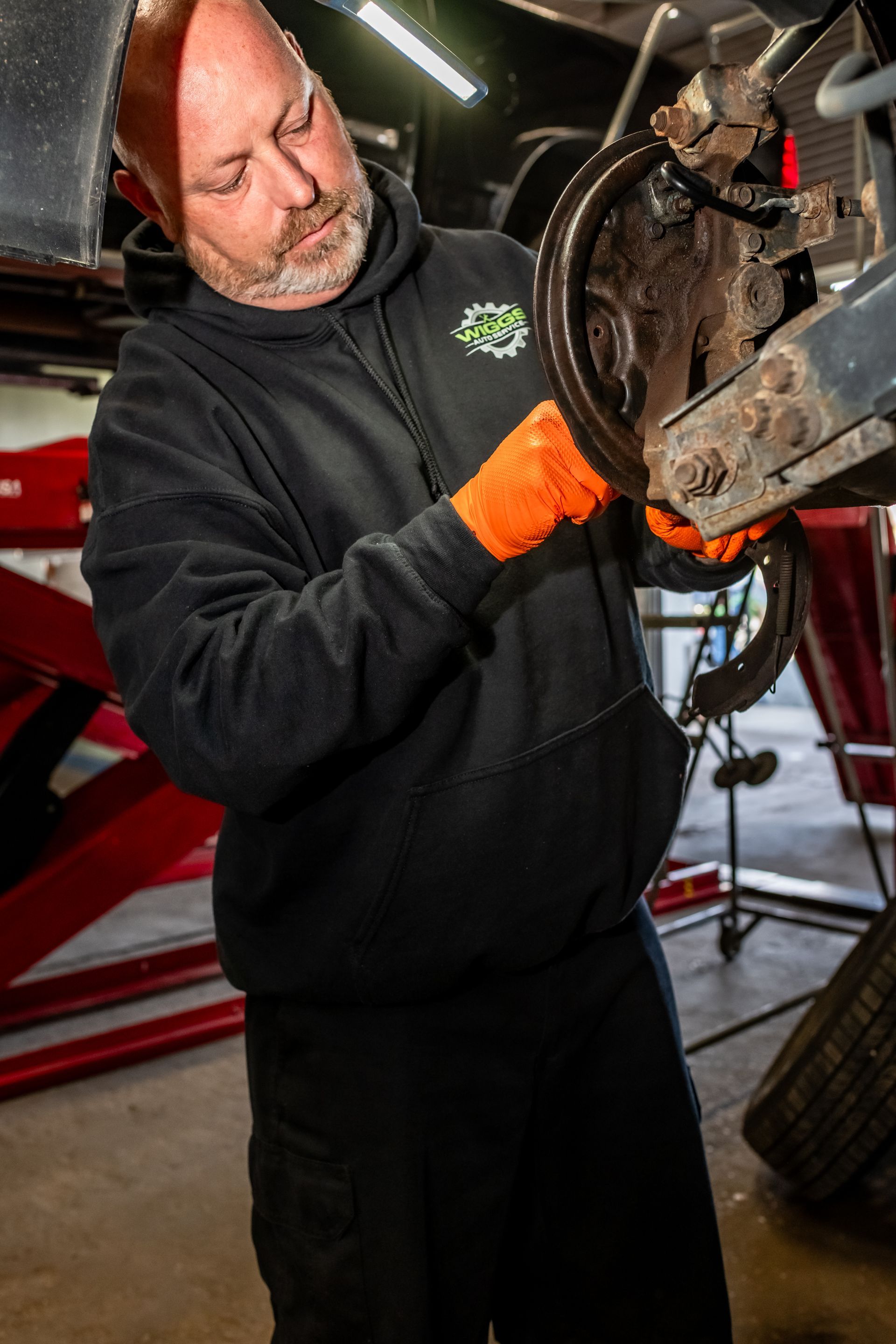A man is changing a tire on a car in a garage.