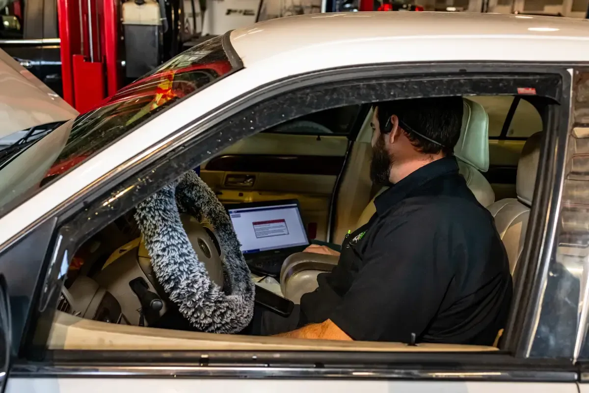 A man is sitting in a car using a laptop computer.