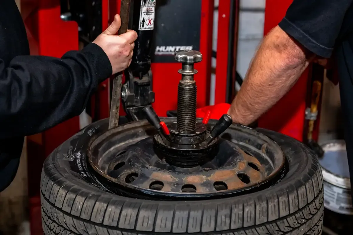 A man is changing a tire on a machine in a garage.
