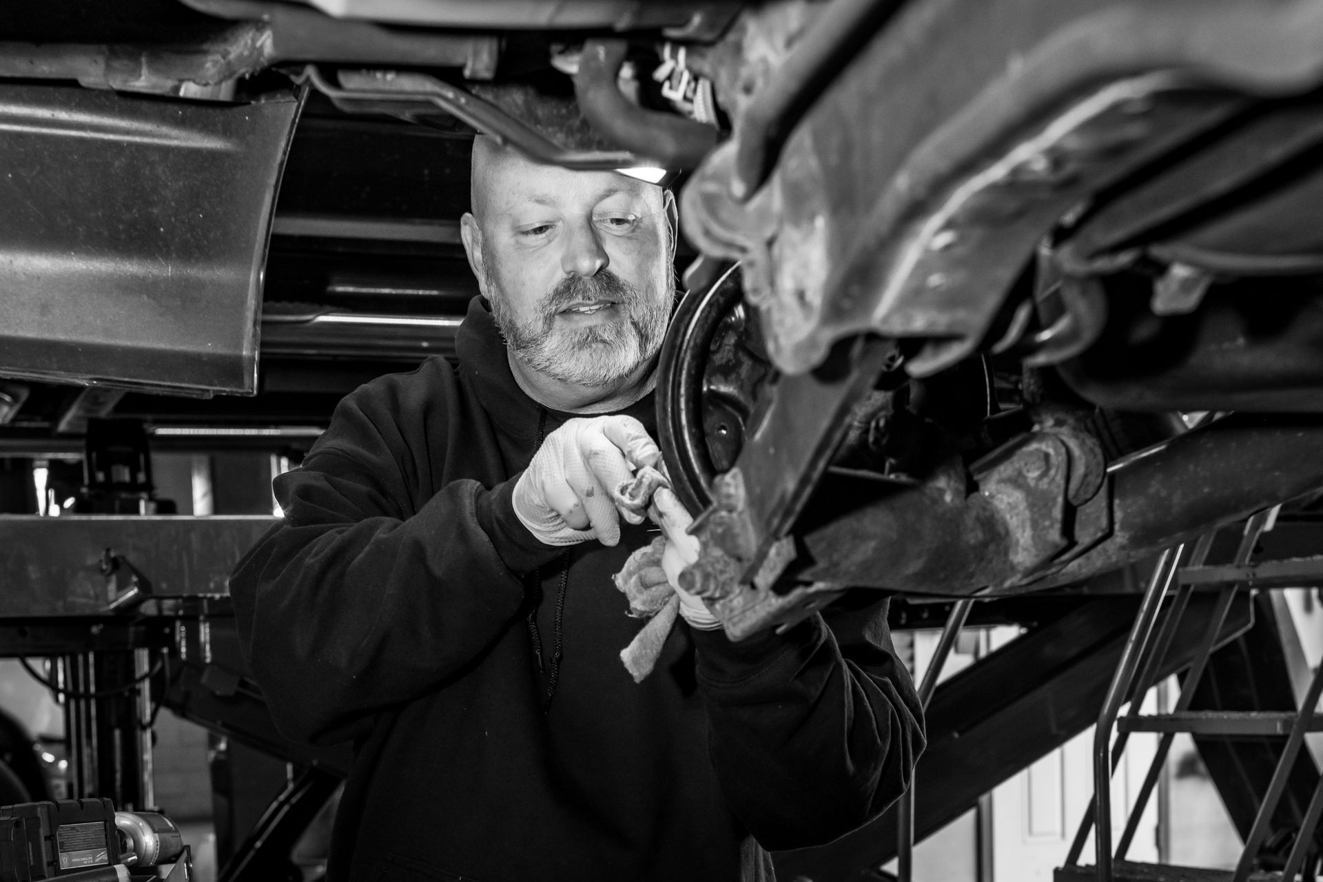A man is working on a car wheel with a wrench.