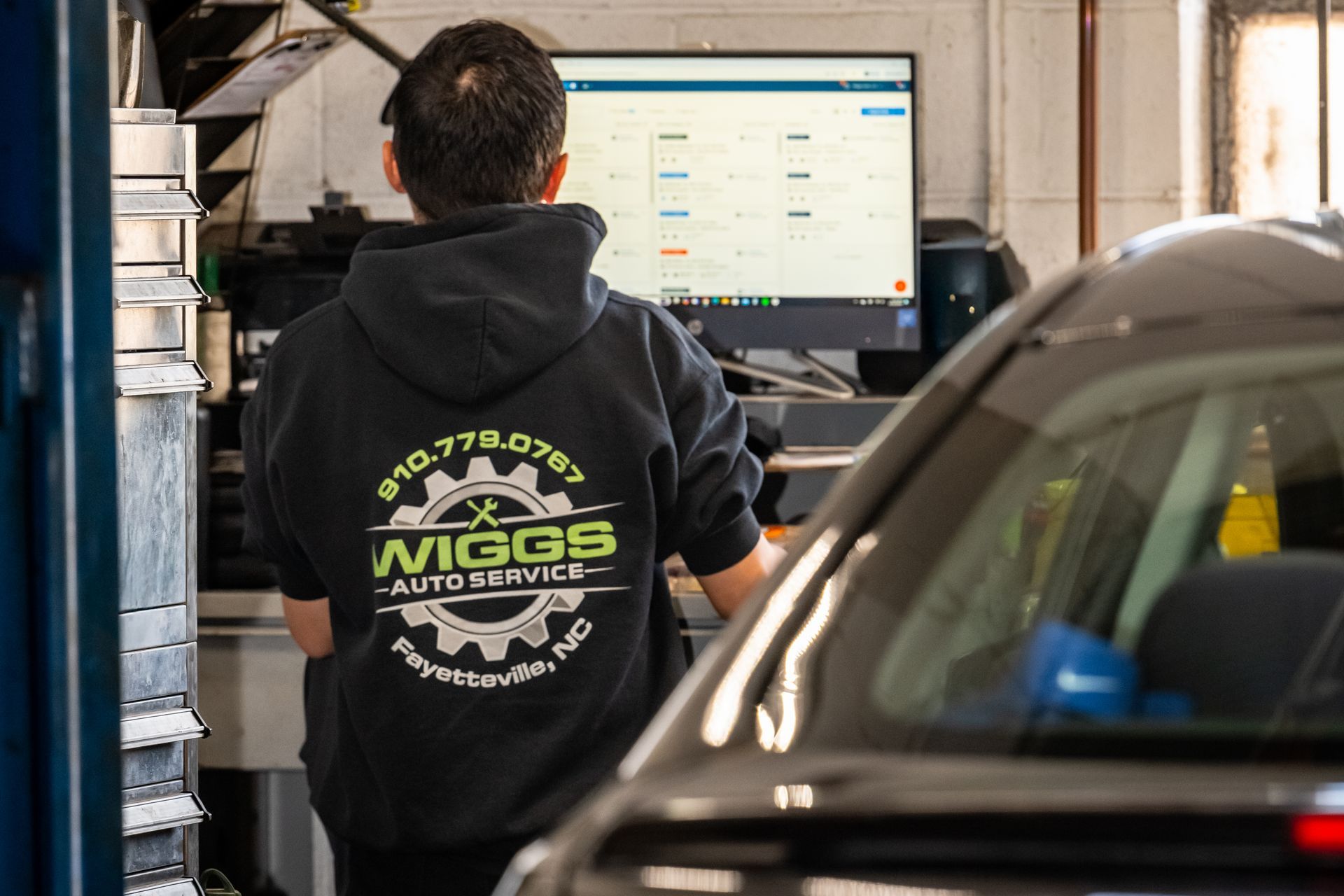 Two men are working on a car engine in a garage.
