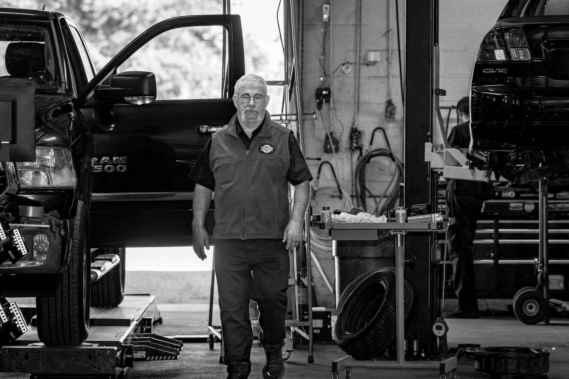 A man is standing in a garage next to a truck.