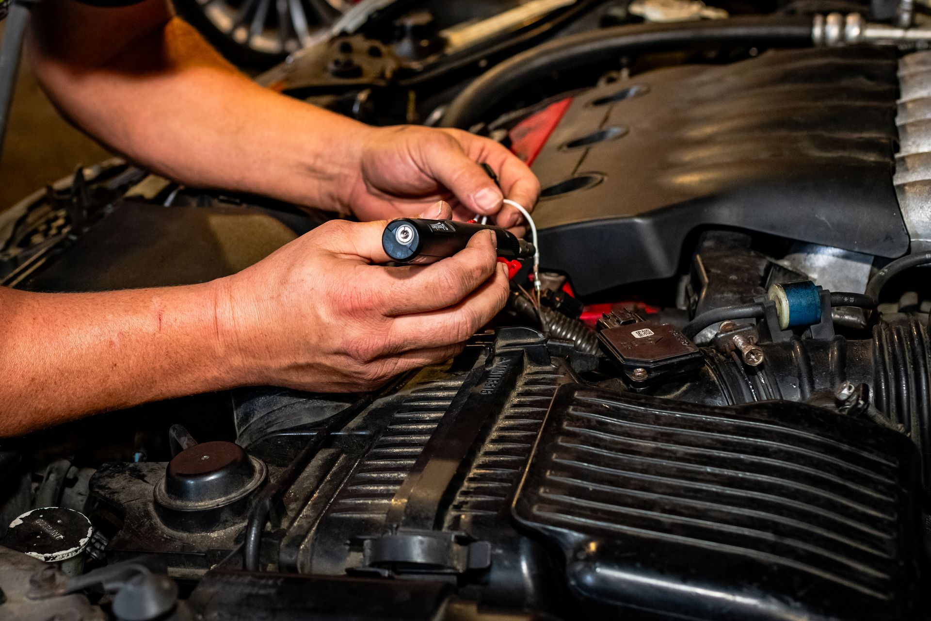 A man is working on a car engine with a wrench.