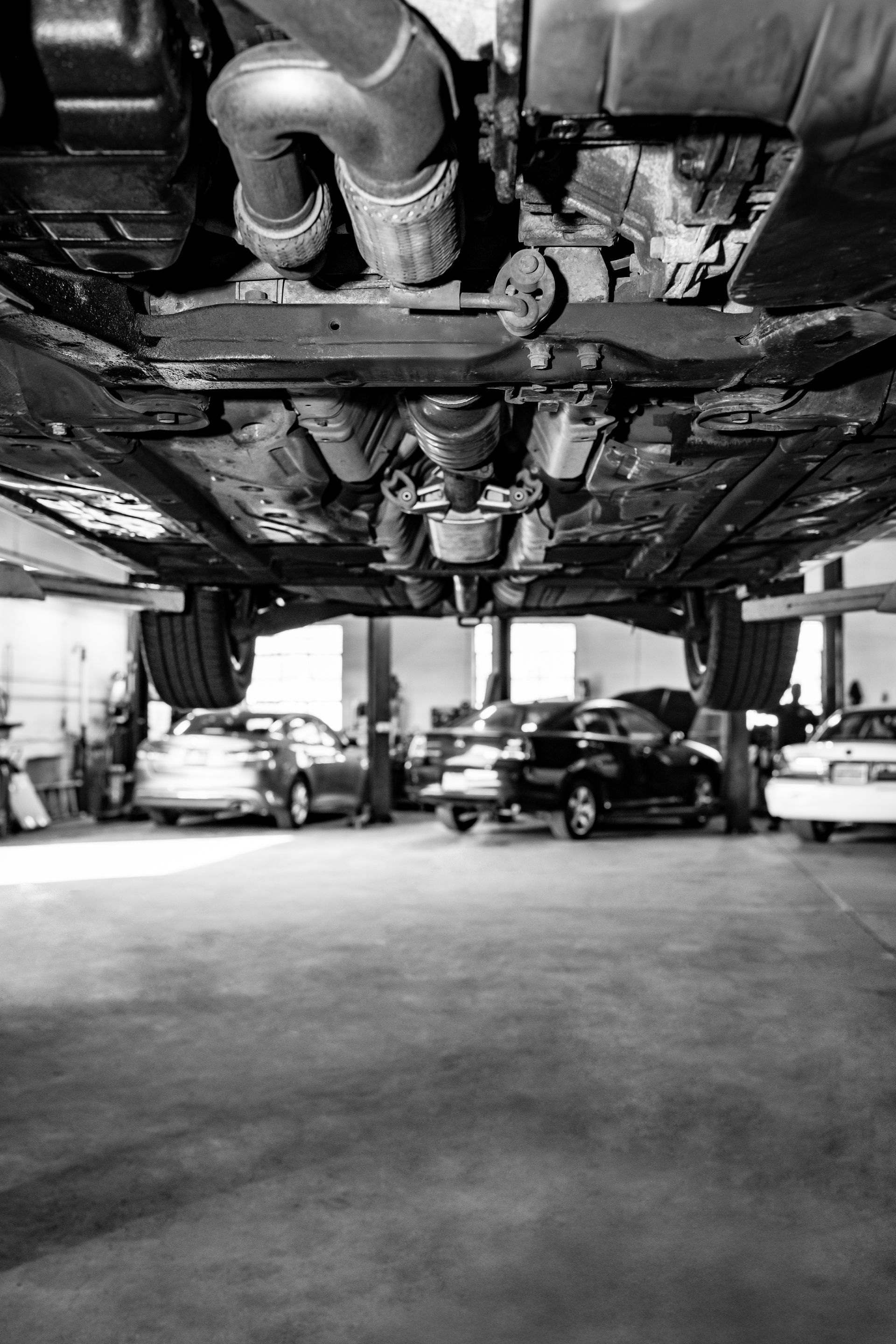 A black and white photo of the underside of a car in a garage.
