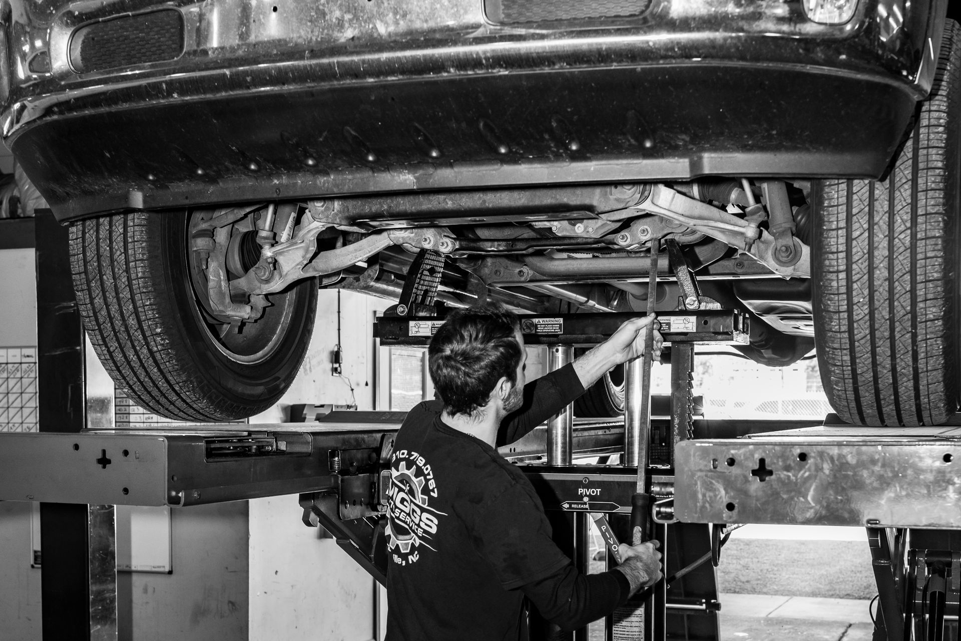 A man is working under a car on a lift.