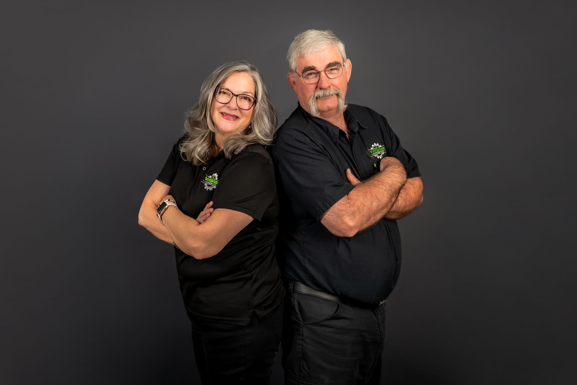 A man and a woman are standing next to each other with their arms crossed.