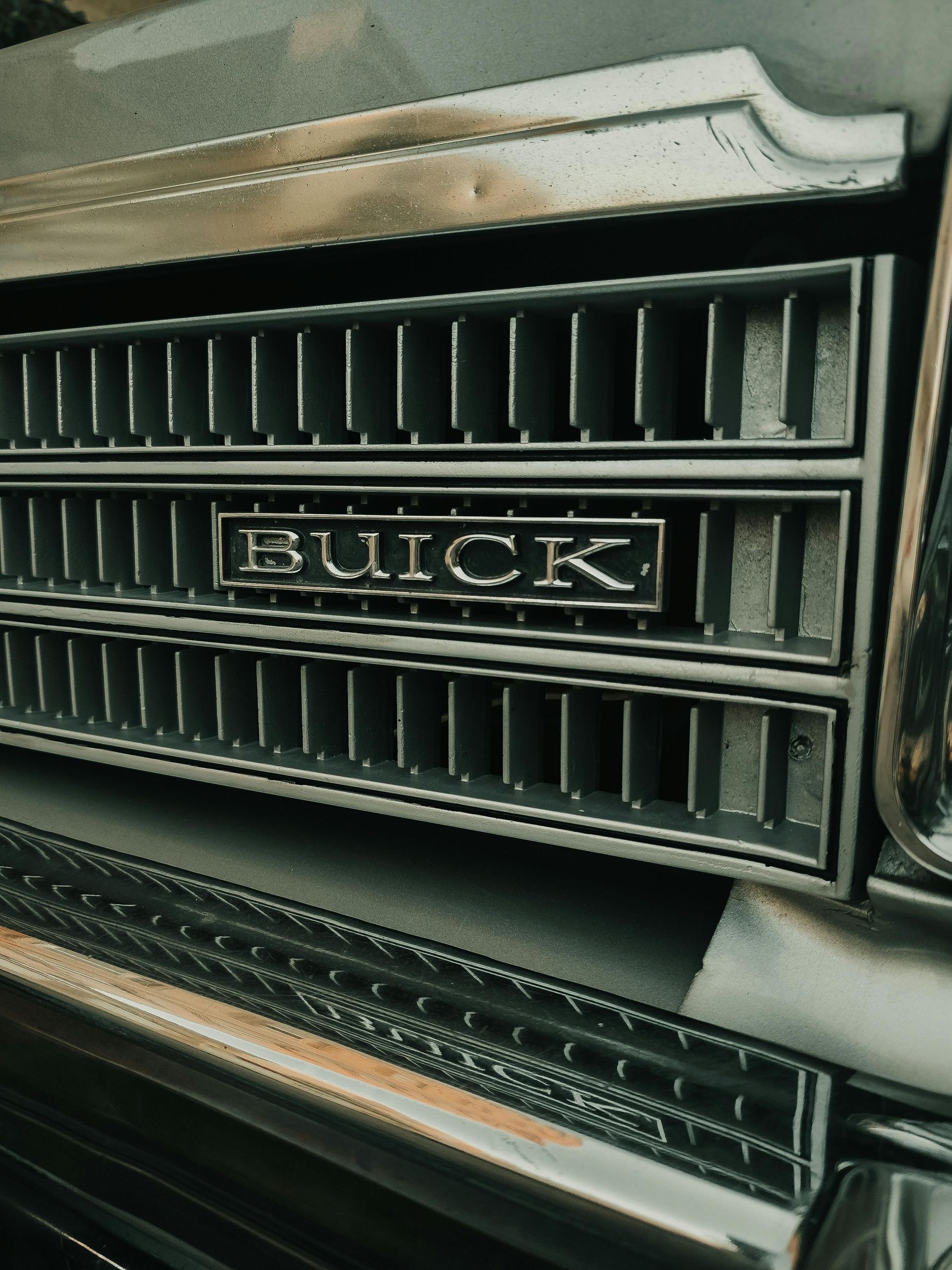 Close-up of a vintage Buick car grille with chrome trim and hood ornament.