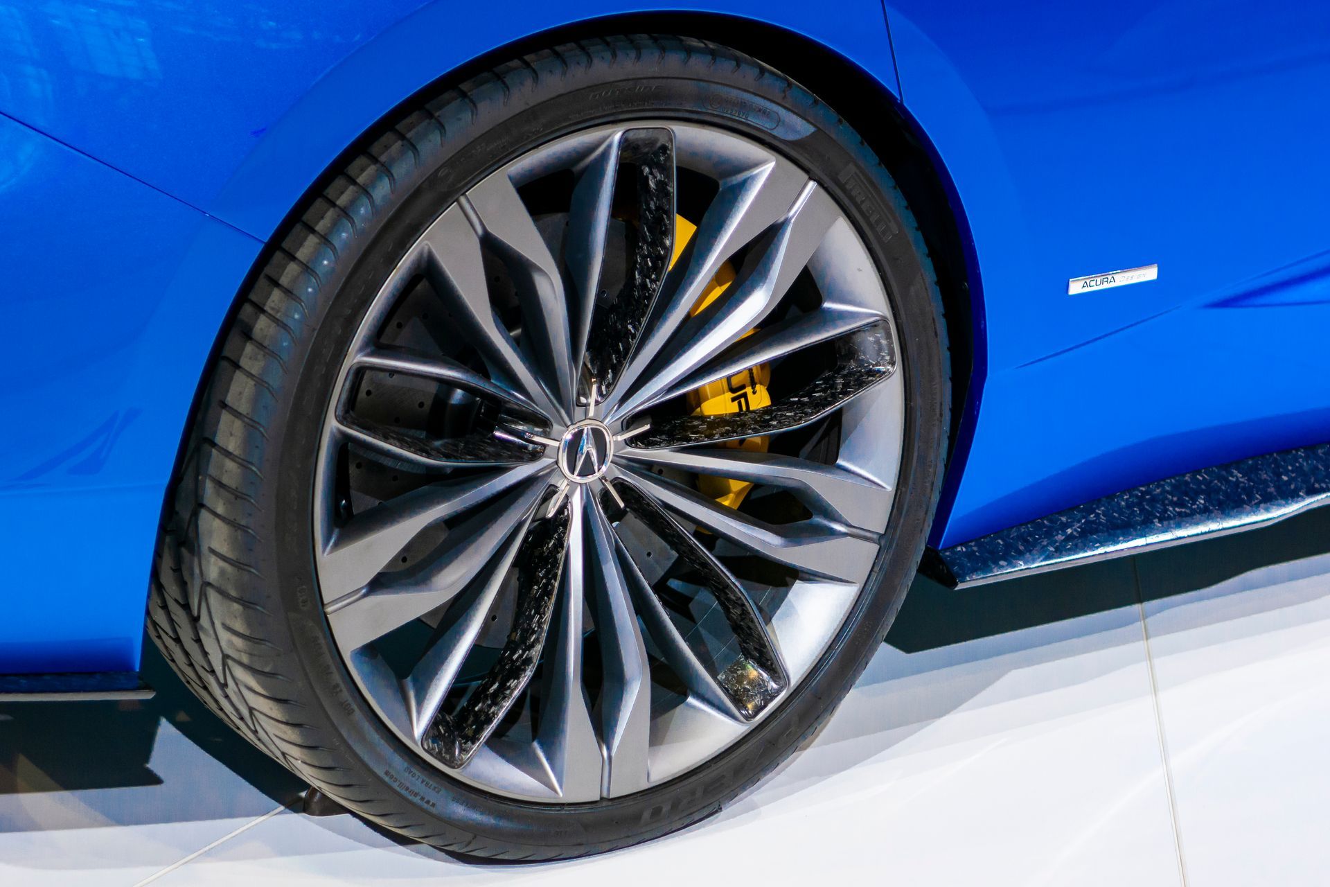 Close-up of a blue sports car wheel with black alloy rim and yellow brake caliper