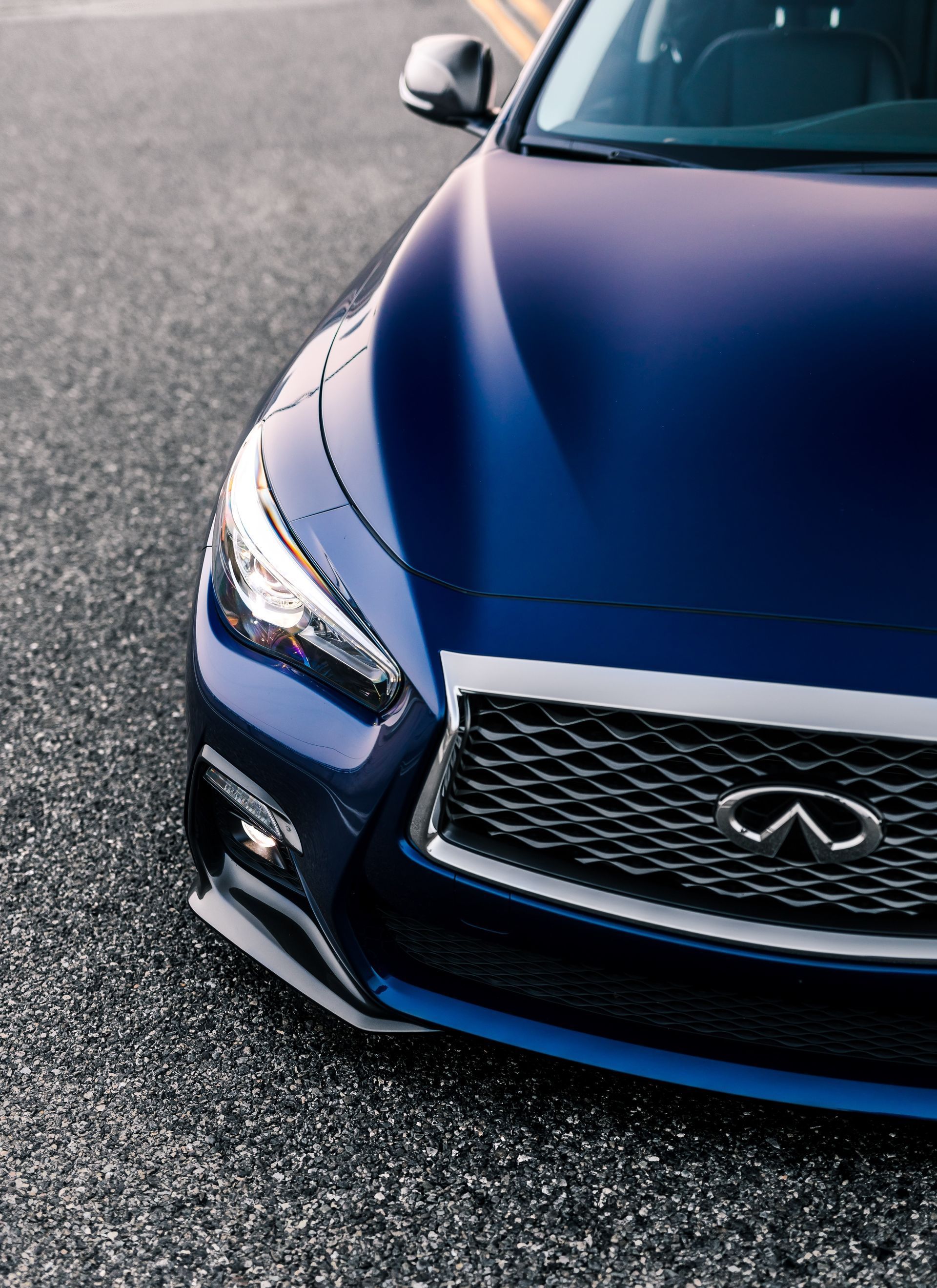 Front view of a blue Infiniti car on a paved road