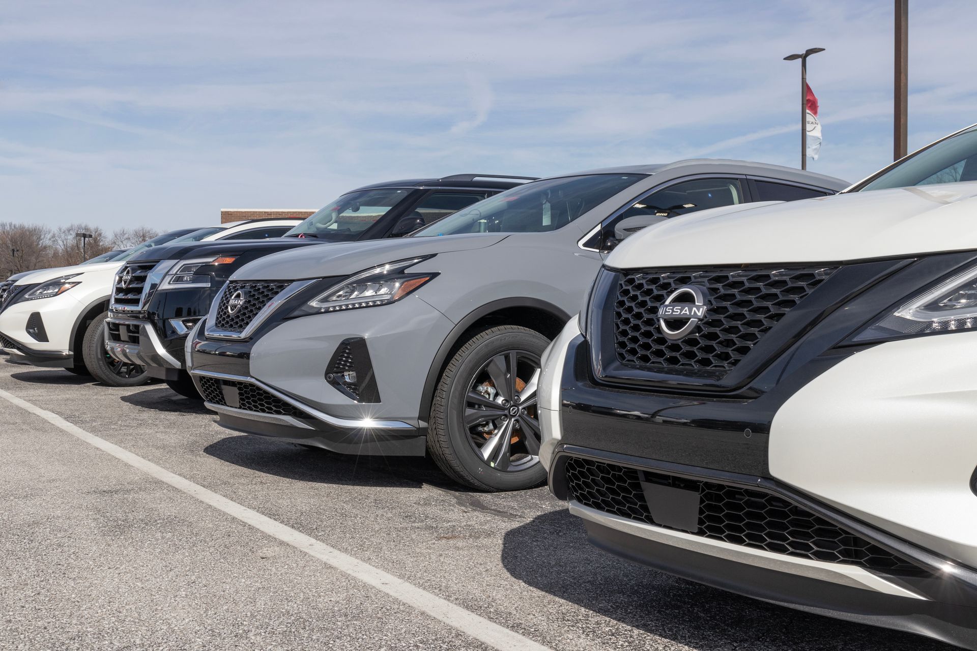 Row of parked Nissan SUVs in a dealership lot on a sunny day