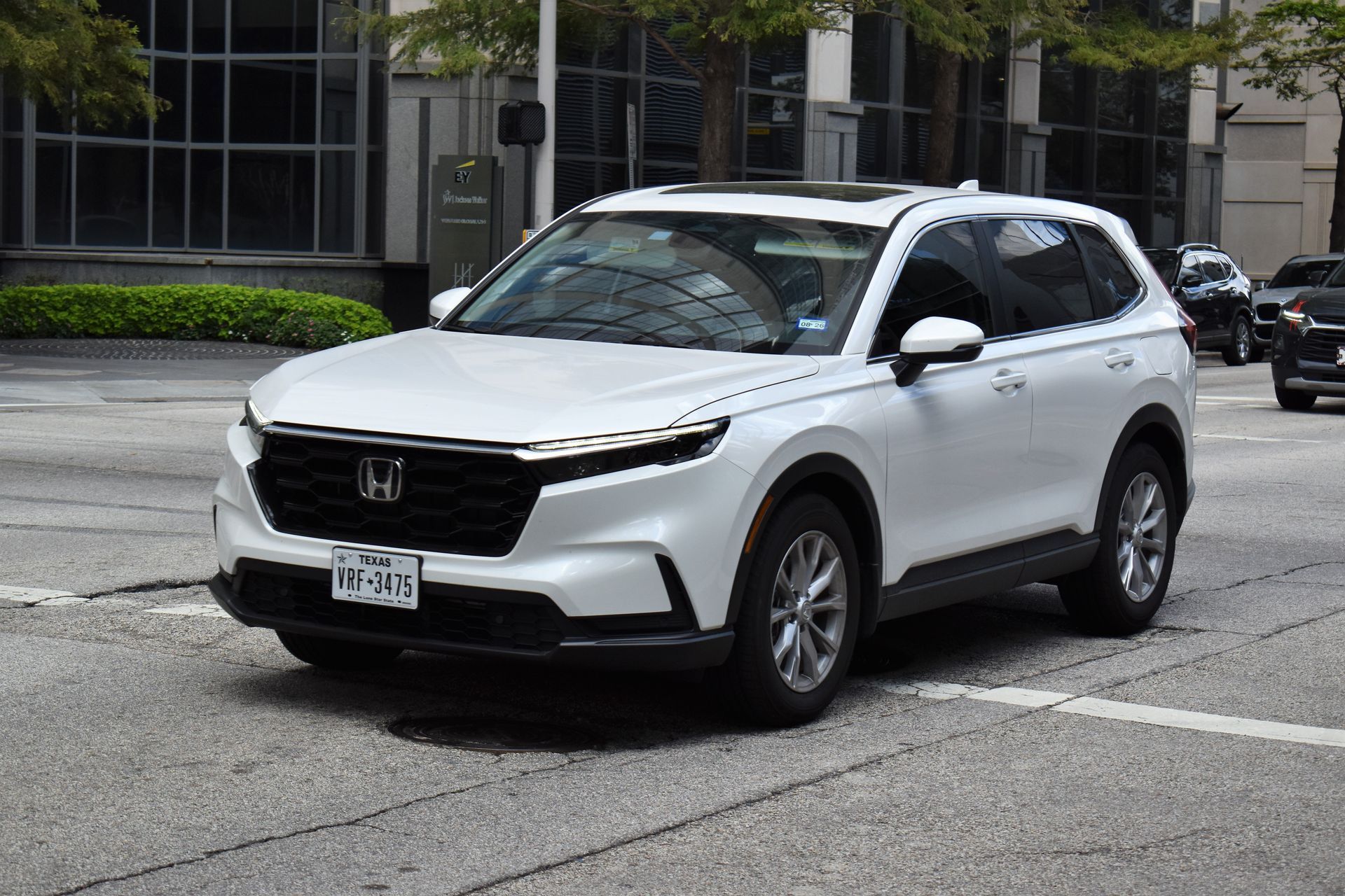 White Honda SUV parked in a city lot beside office buildings, front angled view