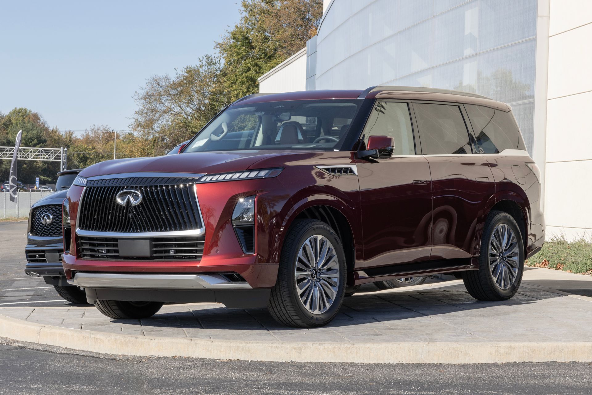 Maroon Infiniti SUV parked outdoors near a white building on a sunny day