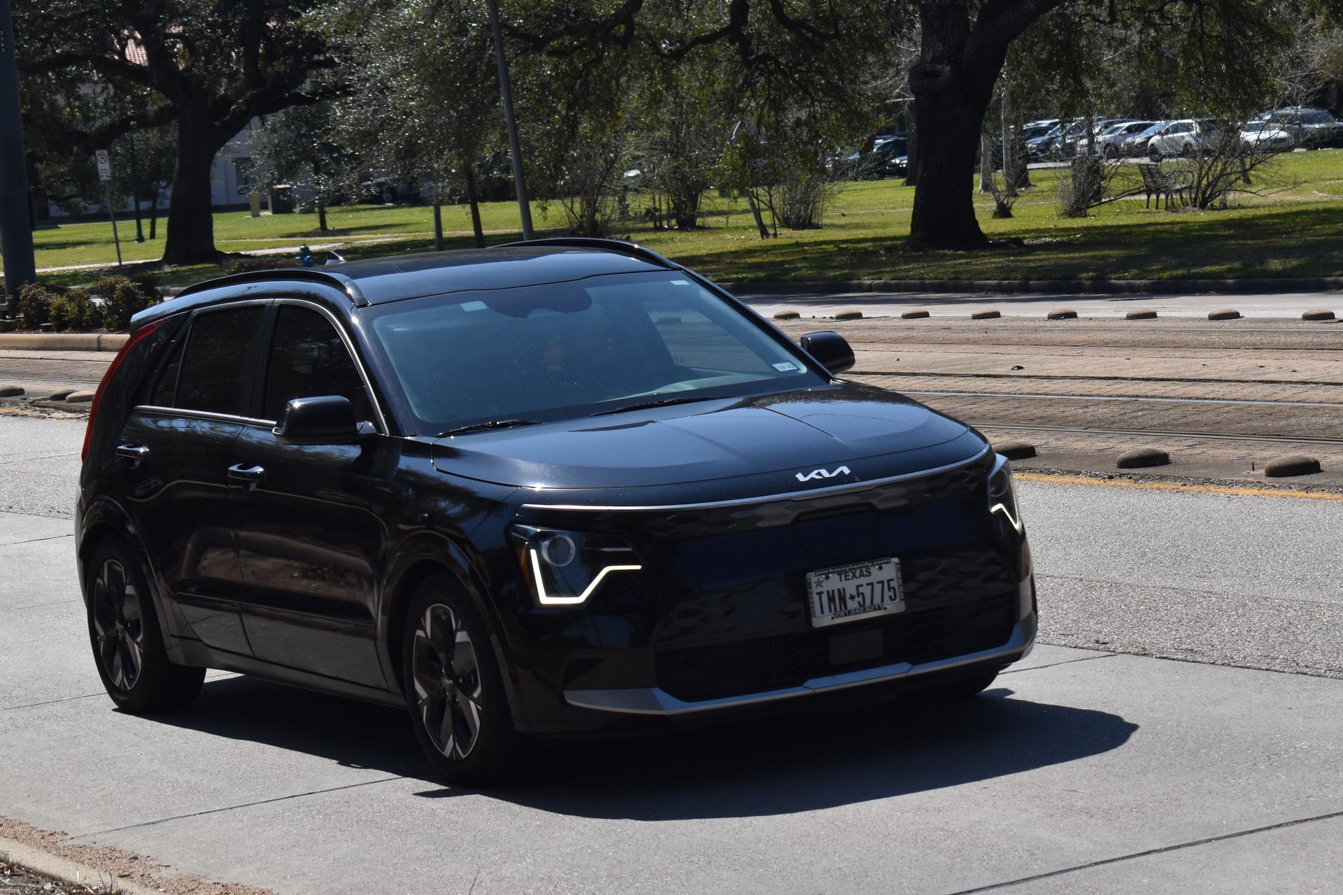 Black SUV driving on a sunny road with trees in the background