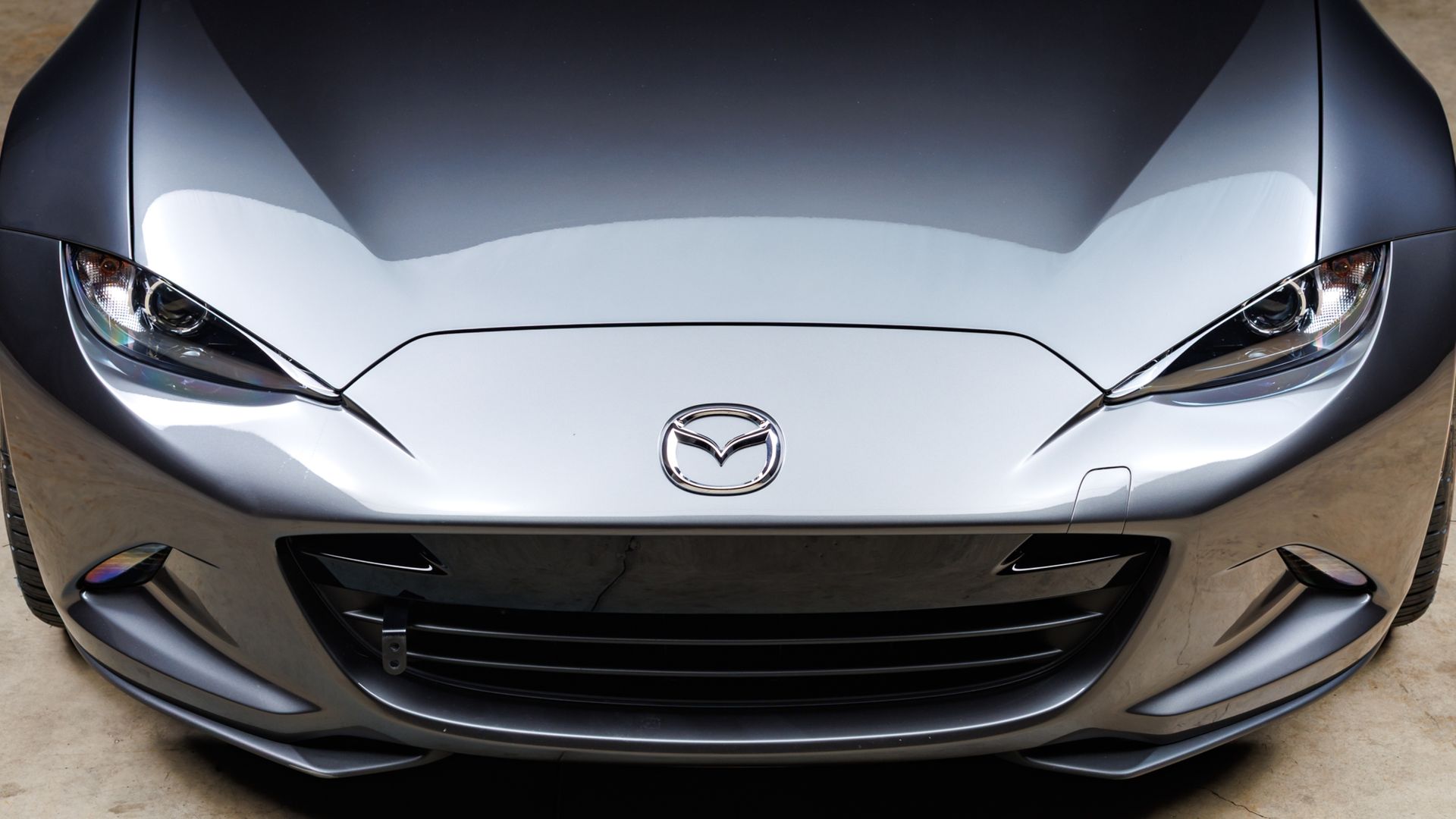 Front view of a silver Mazda sports car with sleek headlights and grille