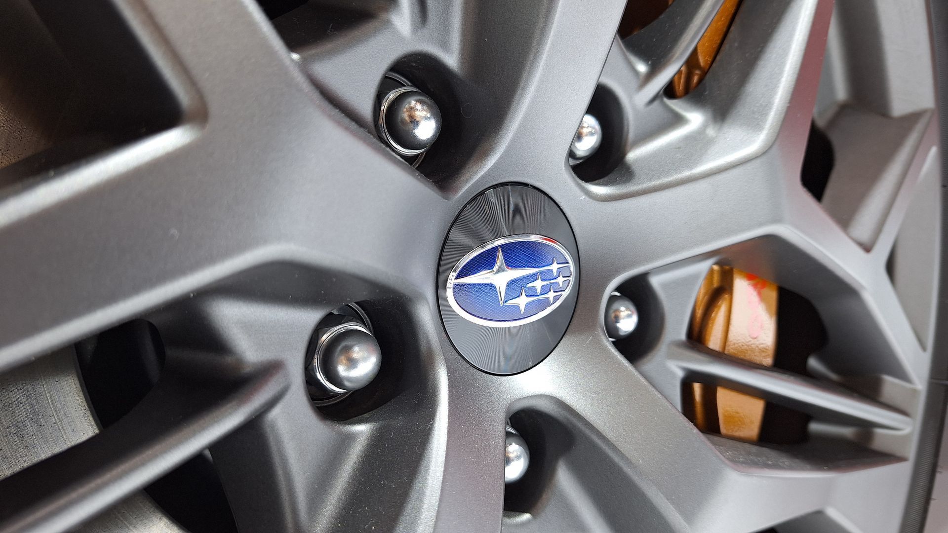 Close-up of a Subaru wheel rim with the blue logo and brake caliper visible