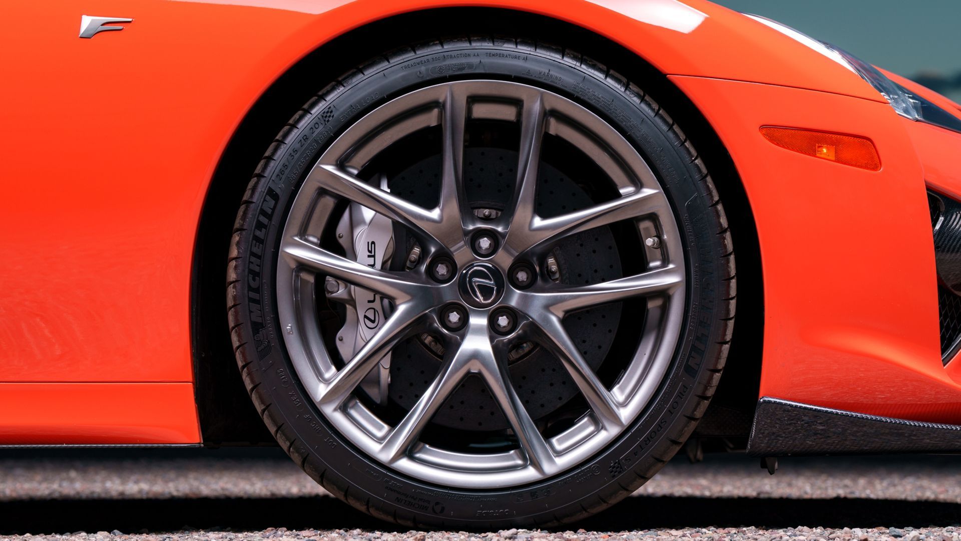 Close-up of a red sports car’s front wheel with a silver alloy rim.
