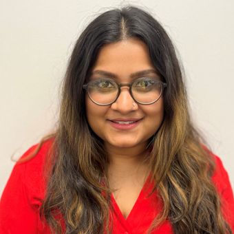 A woman wearing glasses and a red shirt is smiling for the camera.